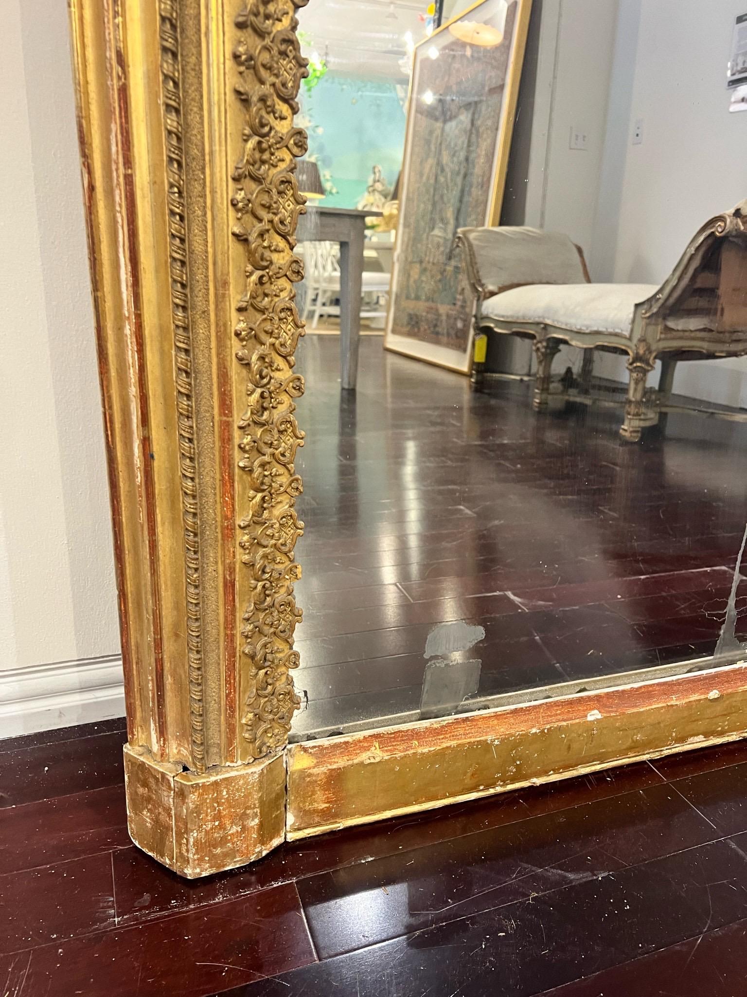 An exceptional large scale mirror sourced in the South of France, this piece measures over 7 feet in height featuring the original diamond dust mirror. Exquisitely carved, gold gilt and backed in wood, this French mirror can be hung but is large