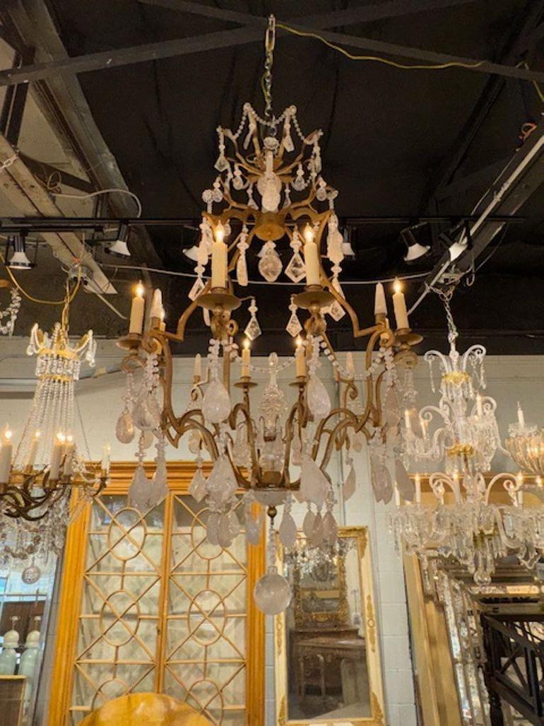 Ce lustre français ancien présente un design luxueux avec des accents de fer doré et de cristal de roche, évoquant un sentiment d'élégance et de sophistication. La combinaison de ces matériaux crée une pièce étonnante qui dégage un charme