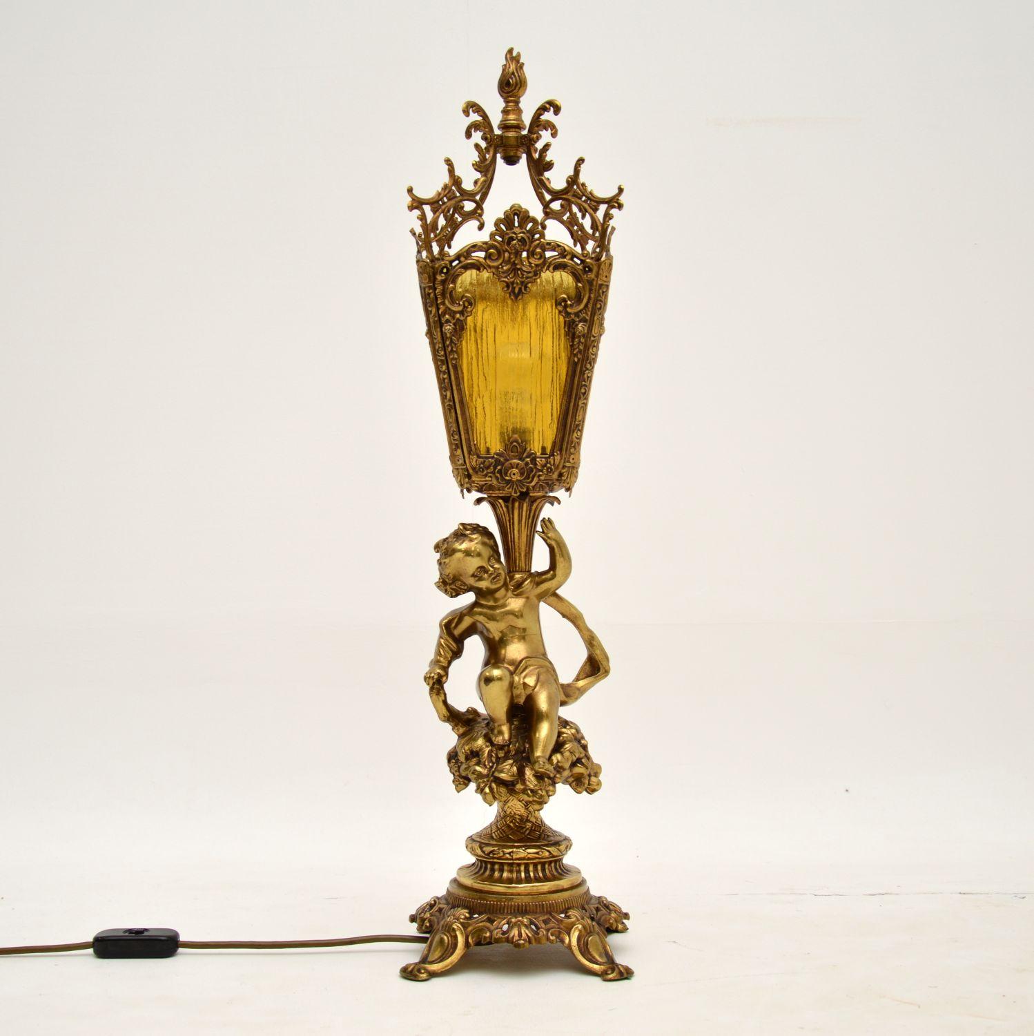 A large stunning antique table lamp in gilt metal, with original glass shade inserts. We believe it’s French & dates from around the 1930-50’s period.

It is of absolutely wonderful quality, with beautiful details all over. The original yellow