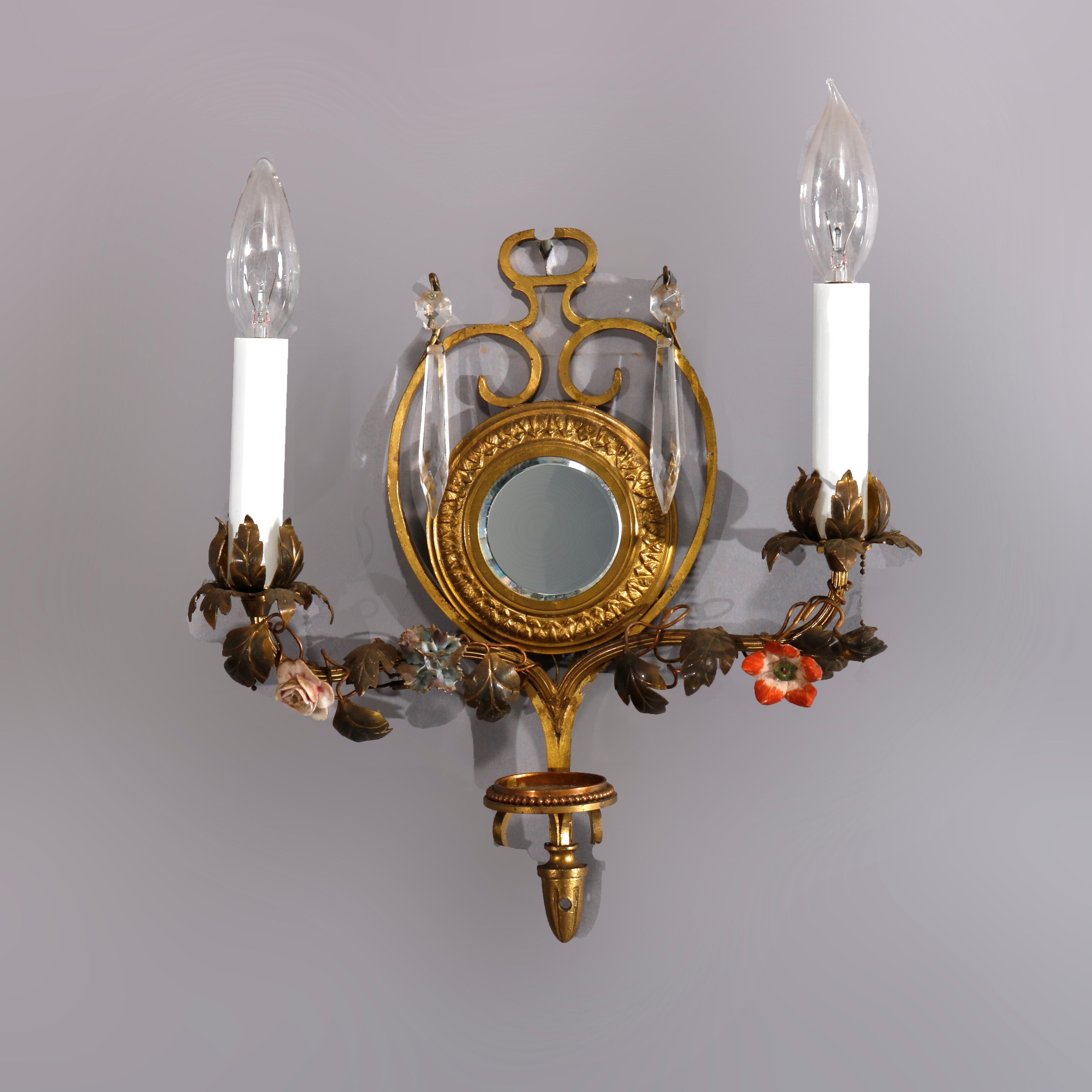 An antique French pair of wall sconces offer gilt metal and brass construction with central beveled mirror having scroll form frames each having two arms with polychromed floral elements terminating in candle lights, circa 1910

Measures: 13.5