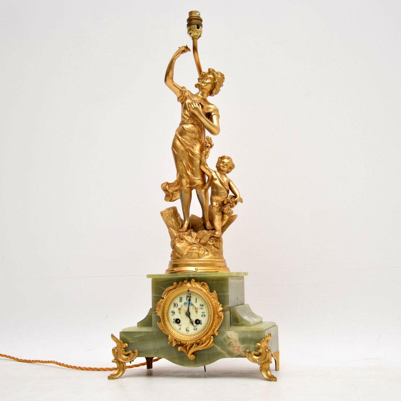 Very decorative large antique French mantle clock encased in onyx, with lots of gilt metal decoration & sitting on gilded feet. On top of the clock section is a very detailed classical gilt metal figure of a woman & a child. This item has also been