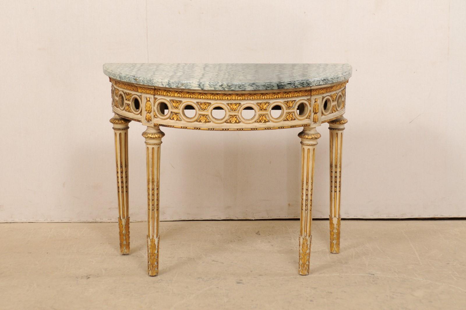 A French beautifully carved and giltwood demilune table with marble top from the 1920s. This antique console table from France features a half-moon shaped marble top which rests upon an exquisitely carved base and legs, adorn with dot-and-line