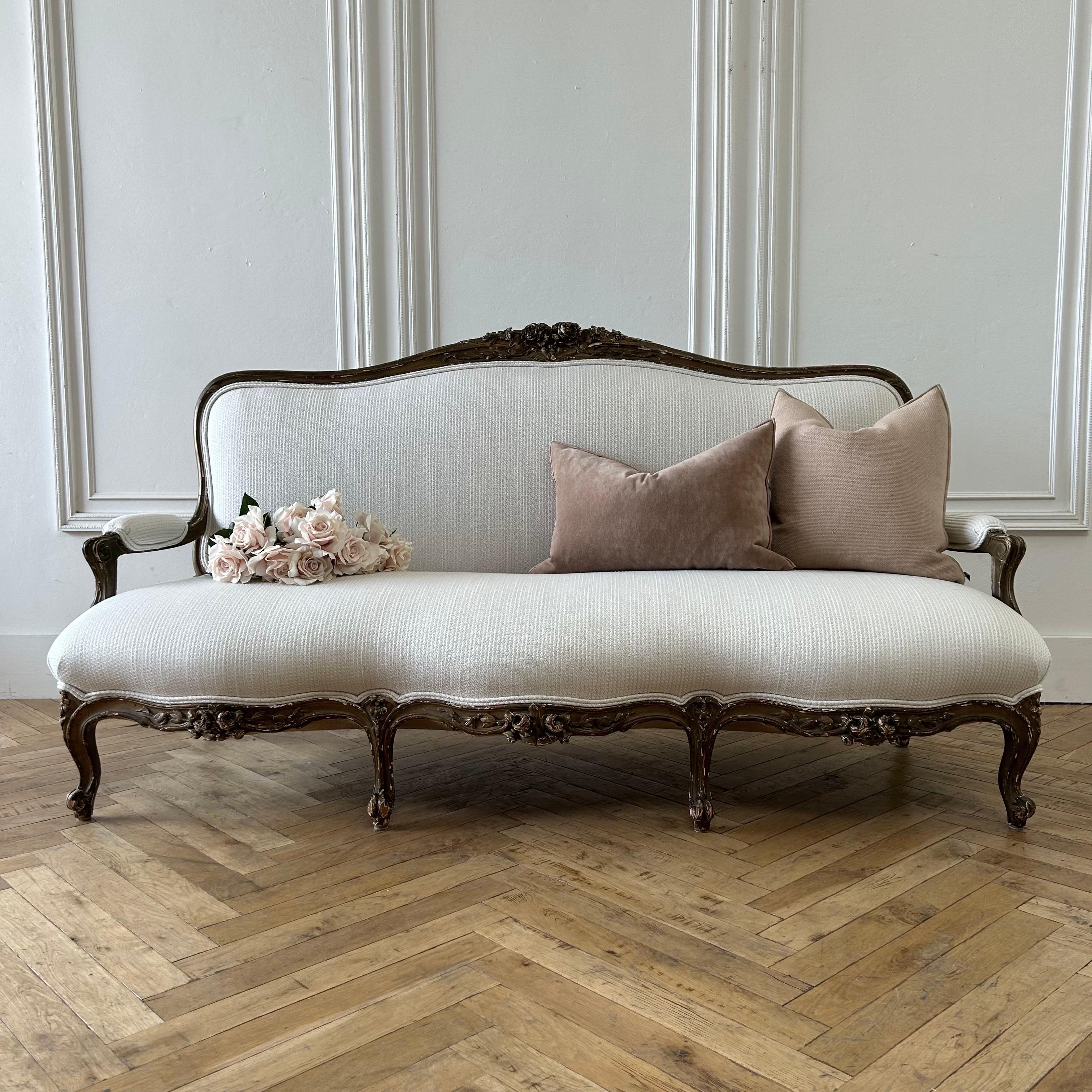 Antique French Gilt Wood Settee from France. Large Carved Roses and Louis XV Style legs, natural chipping, and fading on the original finish, adding a beautiful patina. 
Upholstered in a cashmere and wool Loro Piana Fabric in antique white, knitted