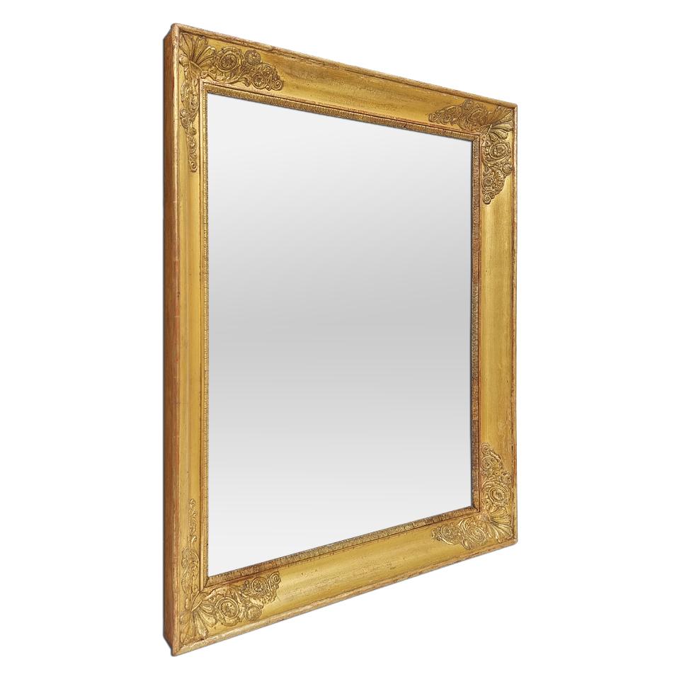 Antique French giltwood wall mirror, Empire period, circa 1810. Antique gold leaf frame, period Empire, adorned with palmettes and vegetal motifs in the form of whorls in the corners, and rais-de-coeur near glass mirror. (Antique frame width
