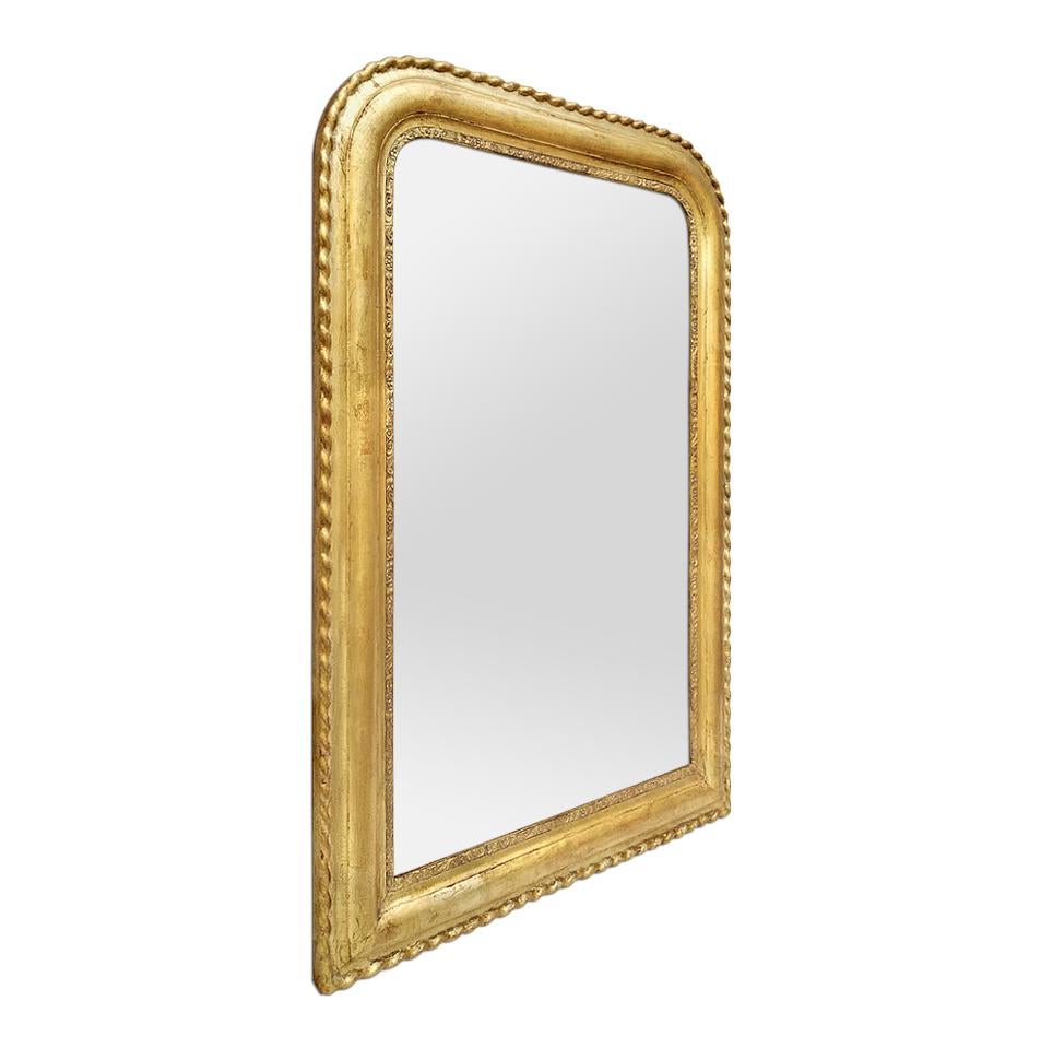 Antique giltwood mirror, French Louis-Philippe style. Antique frame with corrugated decor on the contour, near the glass mirror a decoration of flowers and foliages. Re-gilding to the leaf patinated. Modern glass mirror. Antique frame width 9 cm /