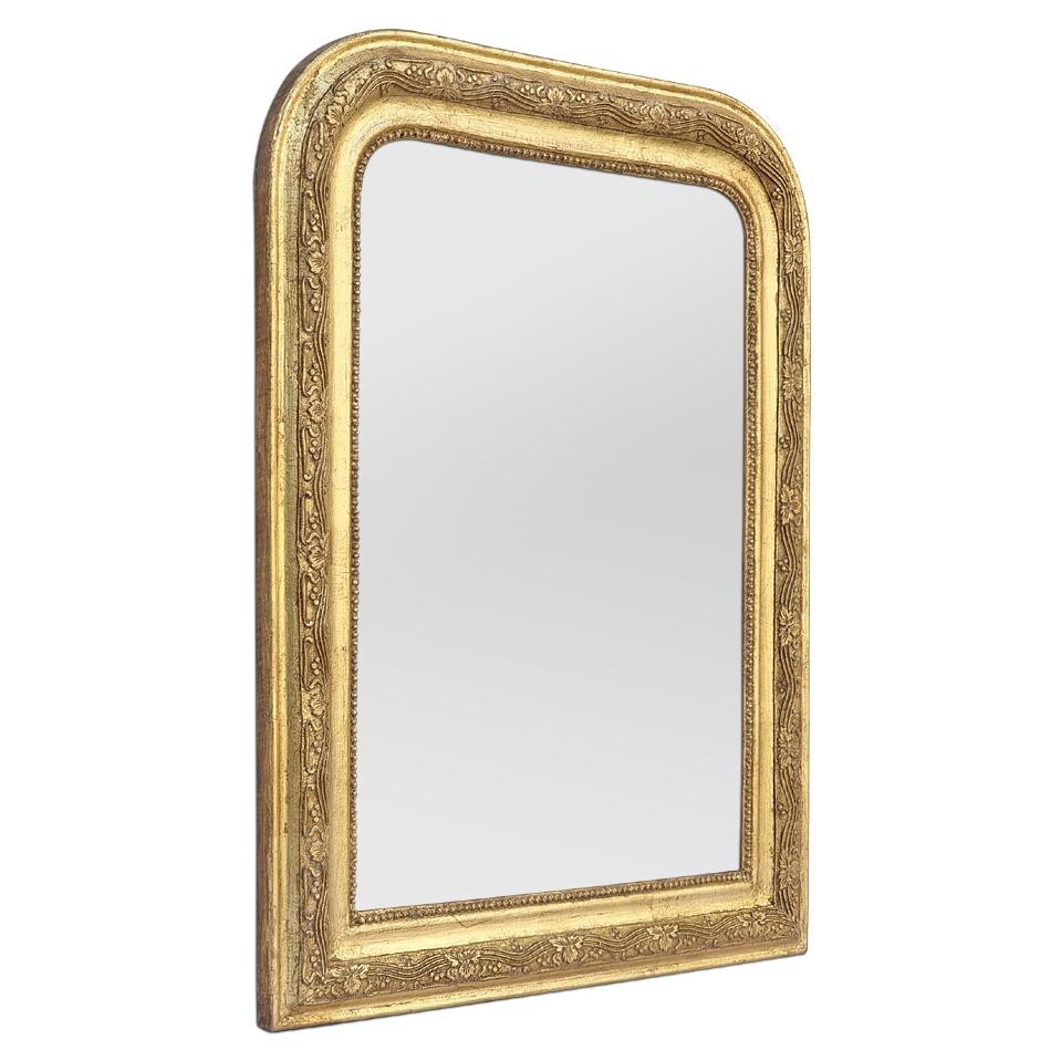 Antique Louis-Philippe French style giltwood mirror, from the 1930's. Antique frame with pearls, around the glass mirror, decorated with foliages and fruits stylised linked by 3 lines at wavy shapes. Re-gilding to the leaf patinated. Antique frame