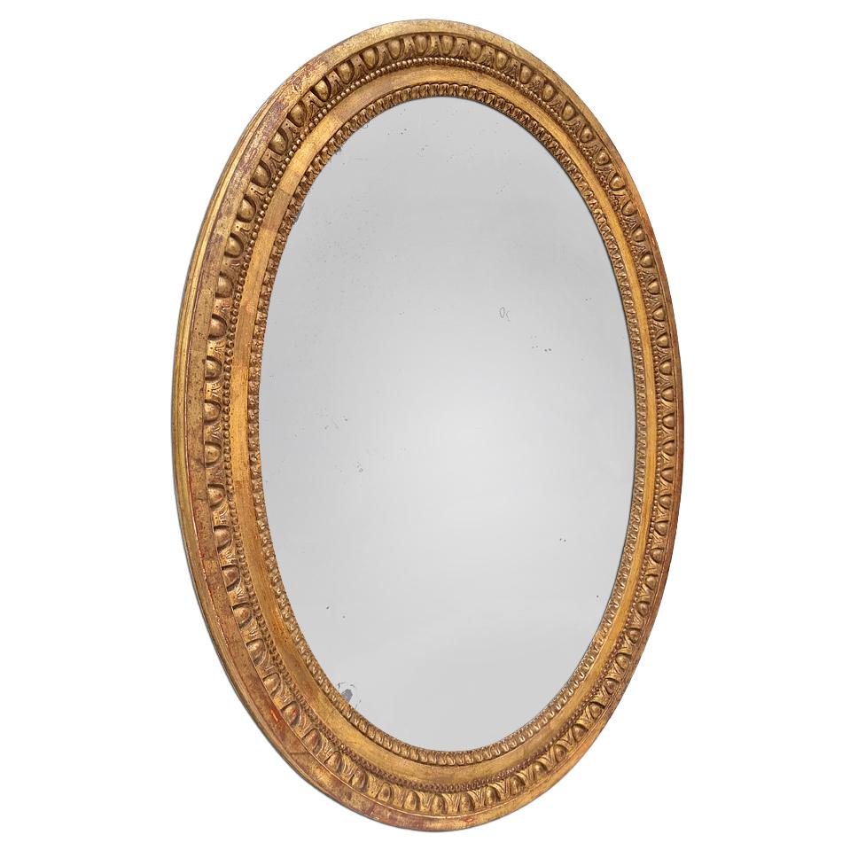 Miroir ovale ancien français, période Louis XVI vers 1780. Cadre en bois de chêne sculpté et doré à la feuille d'or, orné de rais-de-cœur, de perles et d'une frise d'oves. Largeur du cadre ancien : 6 cm / 2.36 in. Miroir ancien en verre au mercure