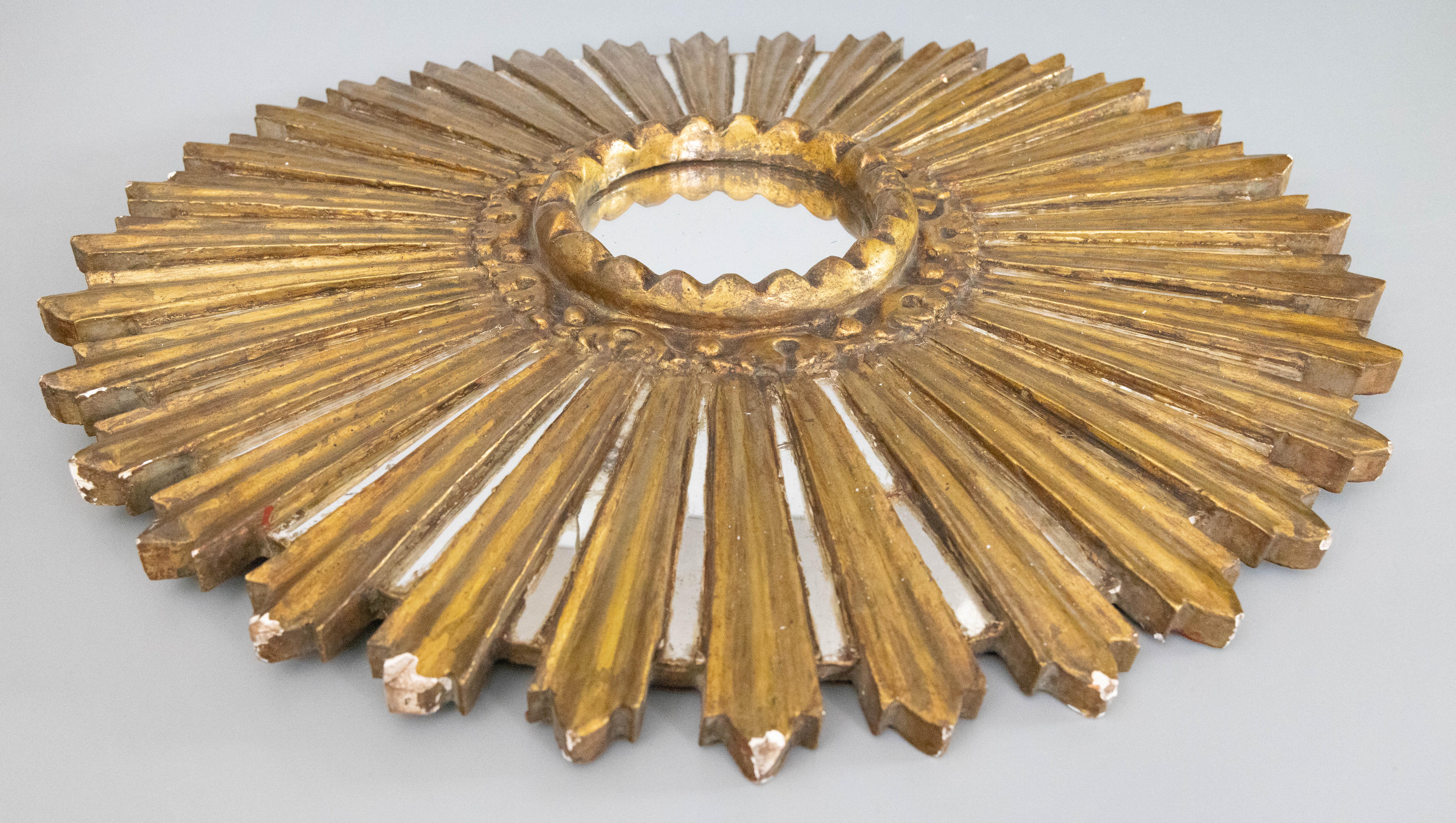 A beautifully carved antique early 20th-Century French giltwood sunburst starburst mirror with the original mirror glass. The lovely gilt patina, antique mirror glass, and finely carved rays make this mirror a rare find. It would make a gorgeous