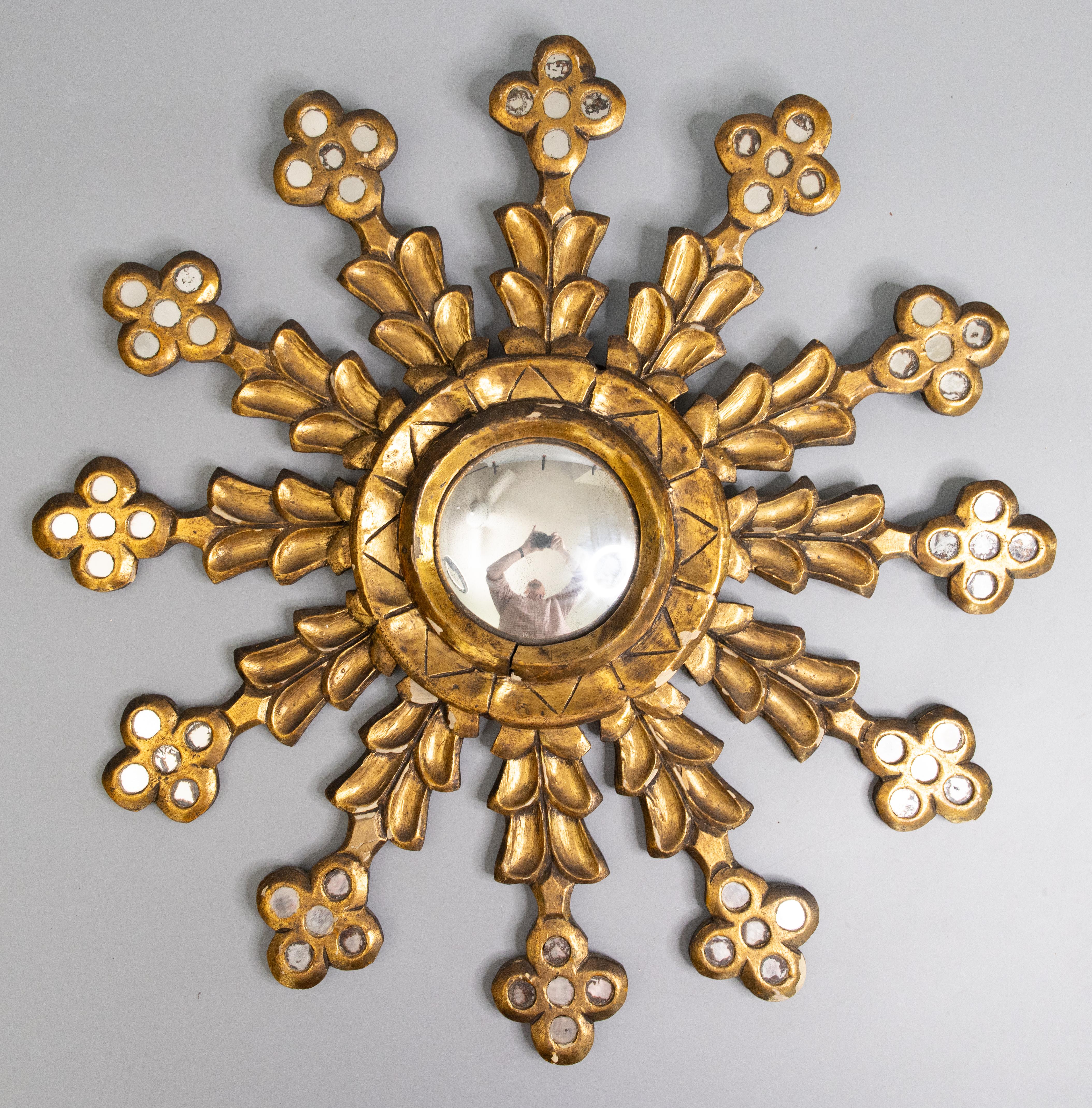 A rare beautifully carved antique early 20th-Century French gilt wood and gesso sunburst / starburst mirror with the original convex mirror glass. This stunning mirror has a lovely snowflake design, aged gilt patina, finely carved mirrored rays, and