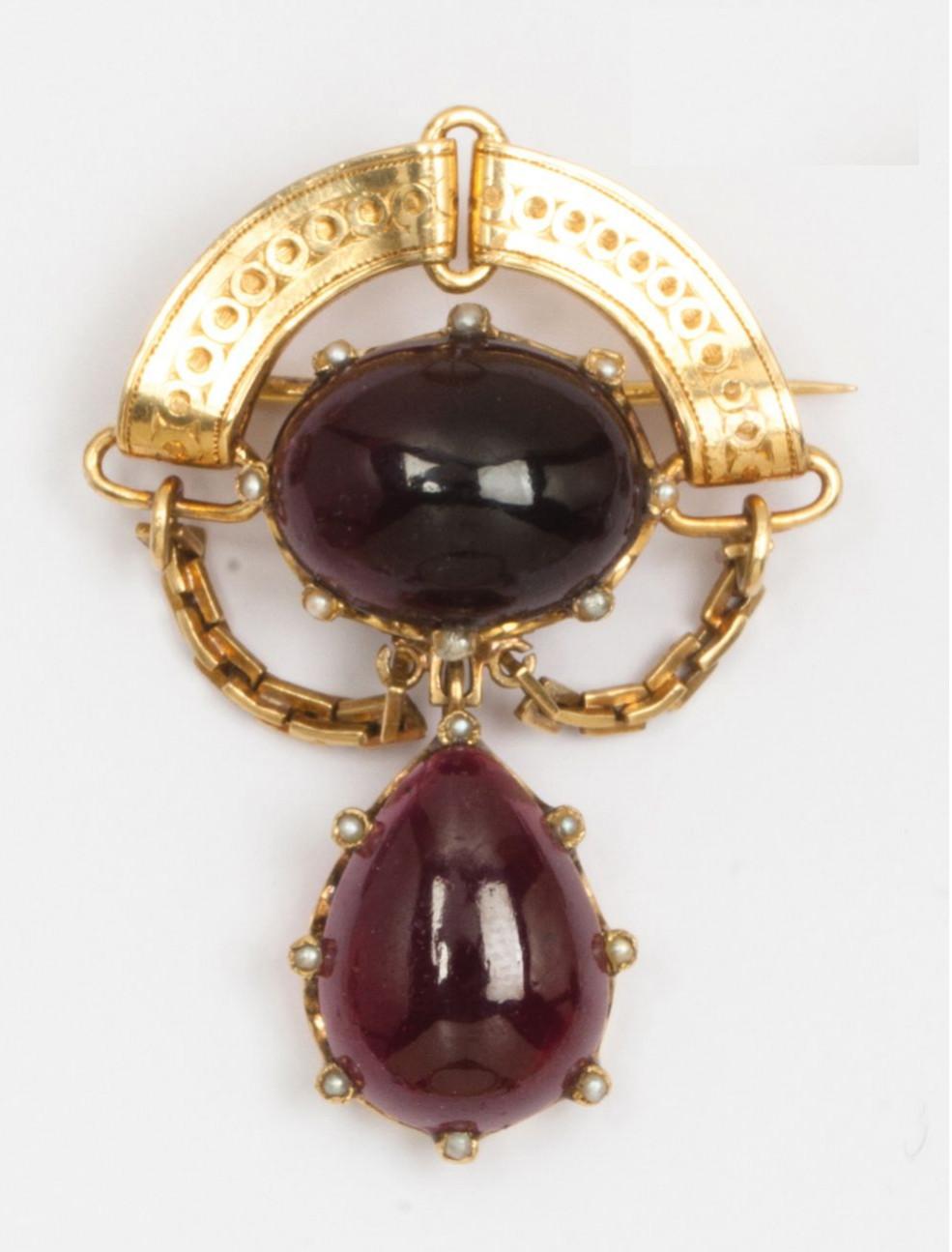 Yellow gold brooch, adorned with two large cabochons of garnets surrounded by seed pearls underlined with a frieze and chains. Dimensions: 5.2 x 3.8 cm
Weight: 17.2g. 