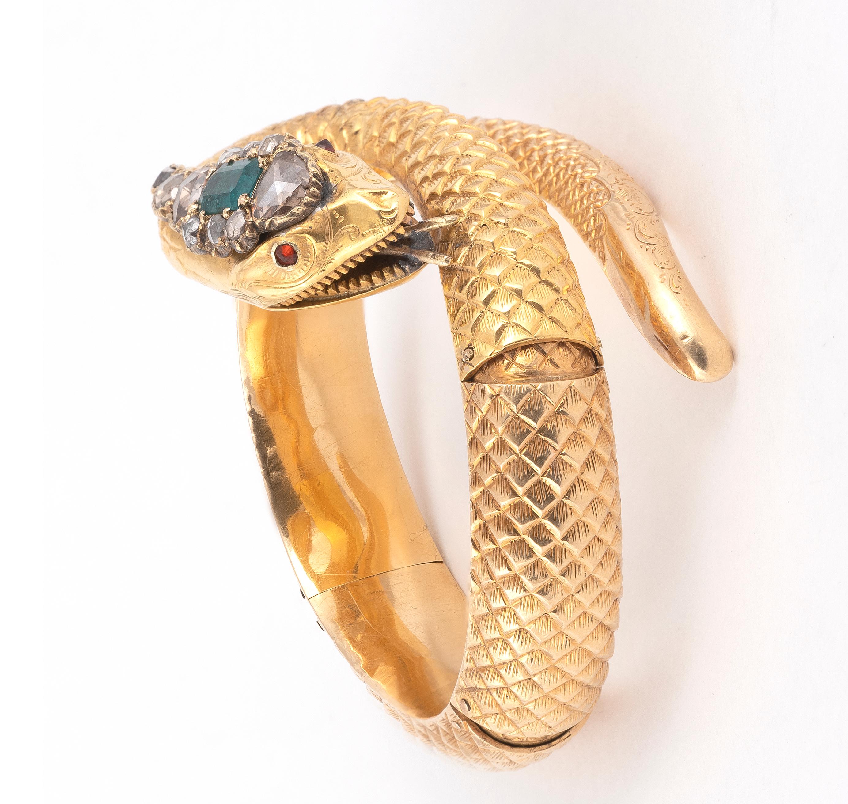 Antique bracelet presenting a snake with a chiselled and textured decoration. Its head is adorned with an emerald and rose-cut diamonds, its eyes composed of red stones. Set in 18K yellow gold. Wrist circumference: 17cm. French mark's.Gross weight: