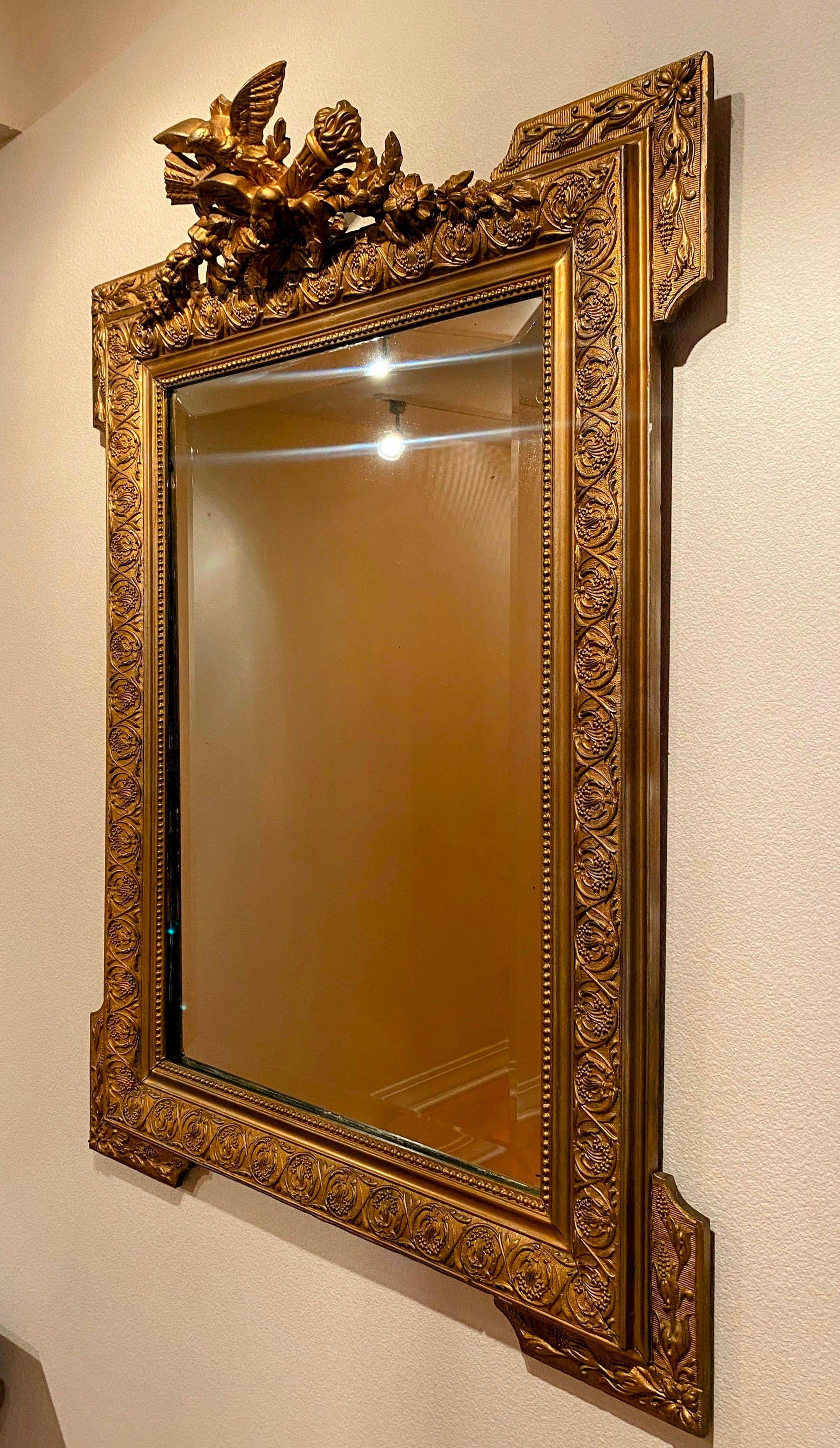 Antique French Gold Mirror. Ornate Gilt and plaster wall mirror, craved gilt eagle on top. Touched up with gold paint later.

Dimensions
29