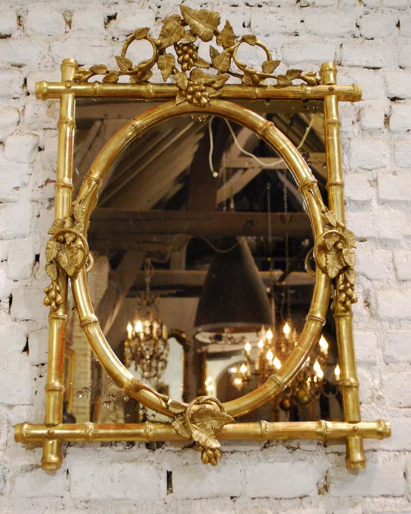 This beautiful French gold gilt mirror was made in France, circa 1880. It is made in the chinoiserie style that came into fashion in the mid-19th century. It has a faux bamboo frame with an oval center mirror. The frame is enriched with wine ranks,