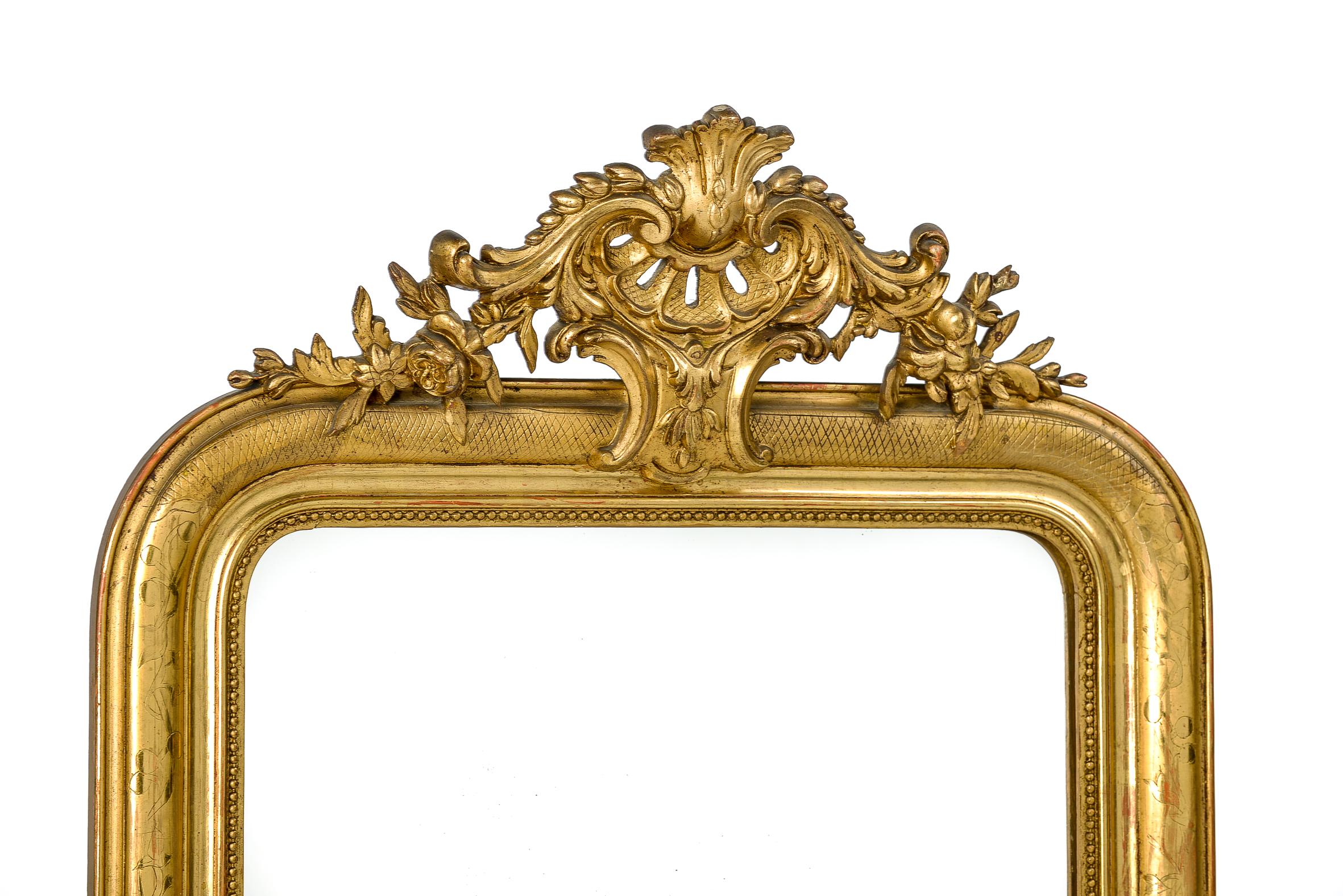 This elegant antique mirror with elaborate crest and intricate etching is made in France, circa 1870.
It has the upper rounded corners typical for Louis Philippe mirrors. The frame is enriched with a beautiful ornate crest built on a central shell
