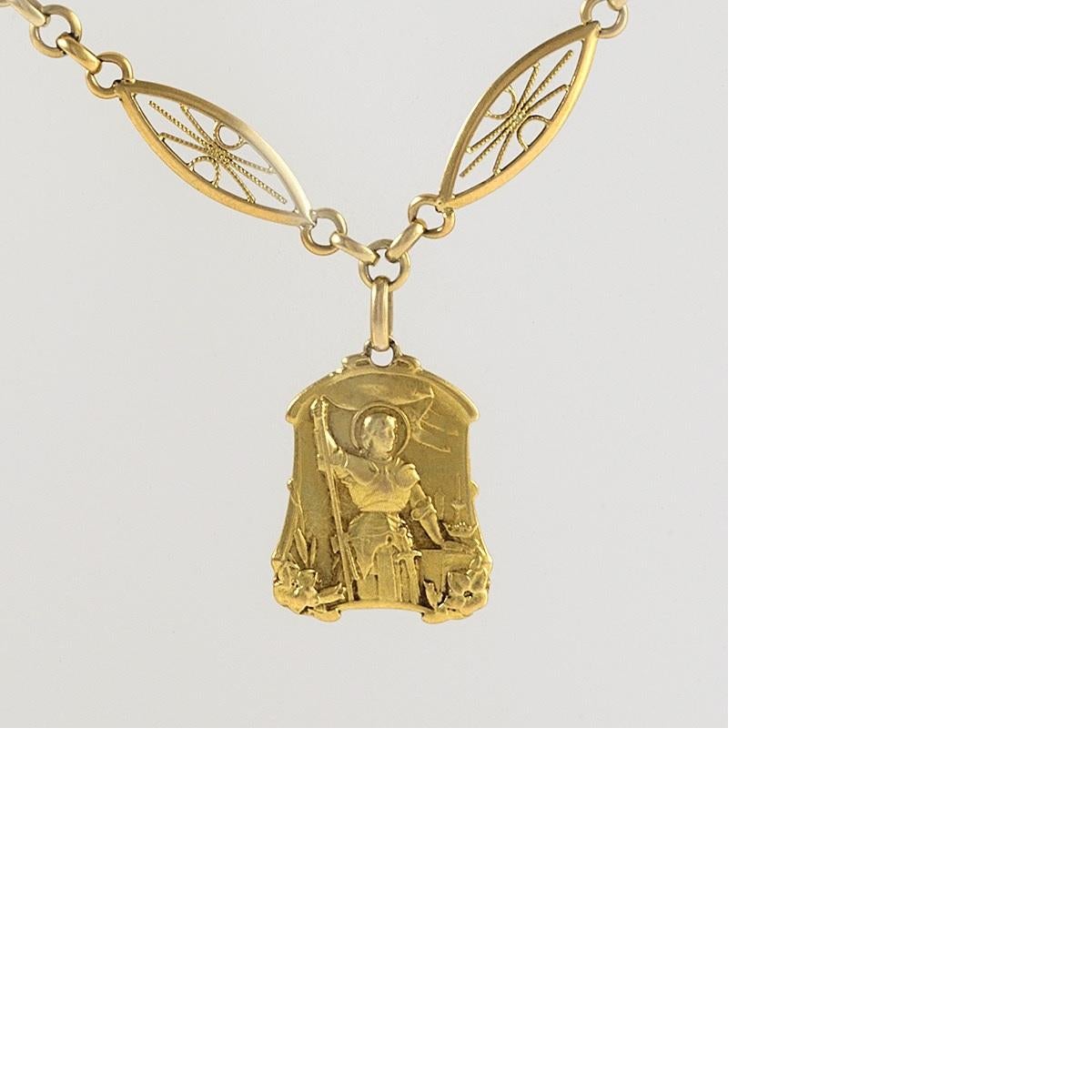 This antique gold French chain, consisting of over five feet of gleaming hand-formed links, suspends a shaped medallion of Joan of Arc. Composed of navette-form links, each centering a radial design of twisted wirework and alternating with circular