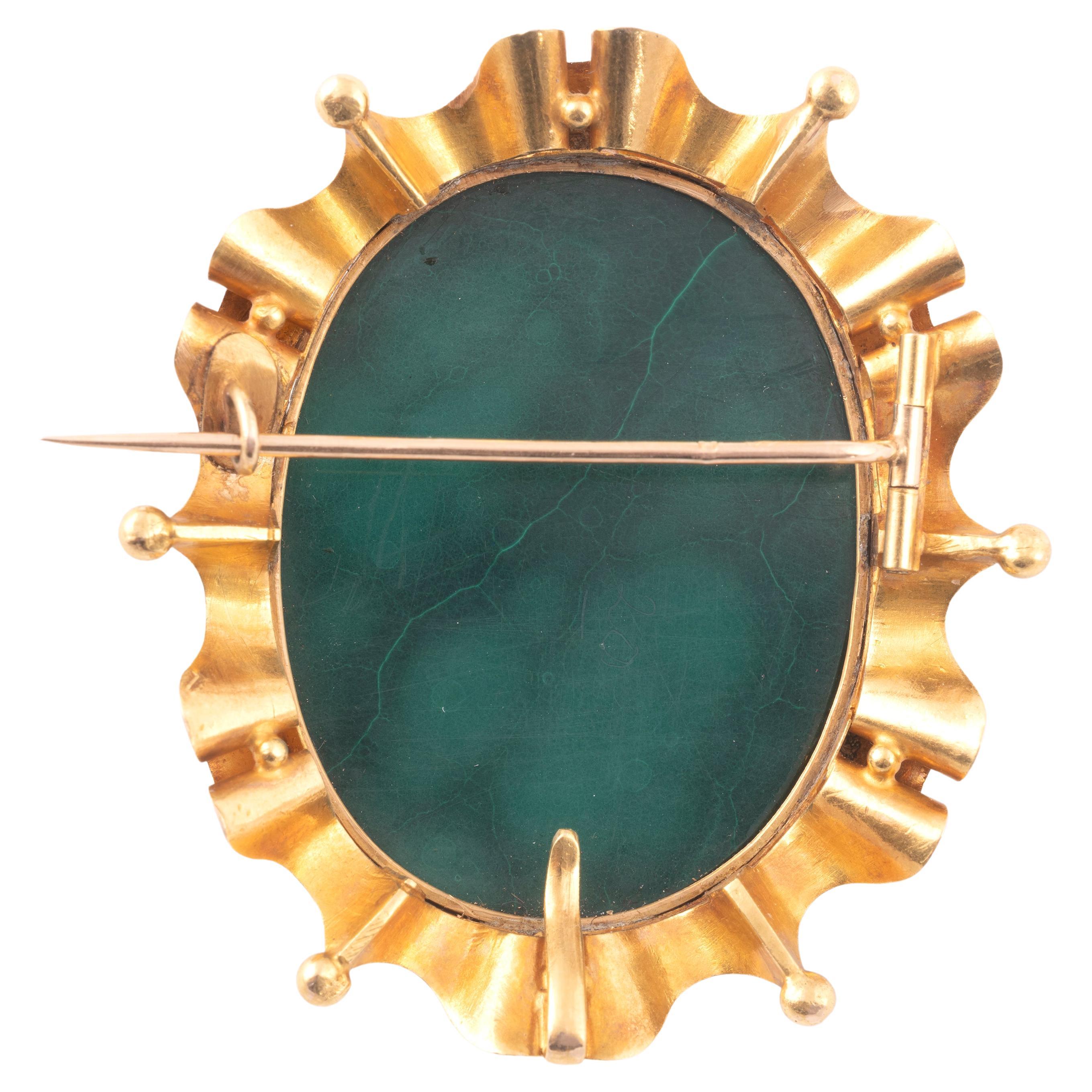 Ruffled oval brooch, which can form a collar watch holder, in 18kt yellow gold centered with a cameo on malachite depicting Cupid in profile, his head turned, holding his loose bow, in closed setting, and surrounded by a ribbon, partially beaded,
