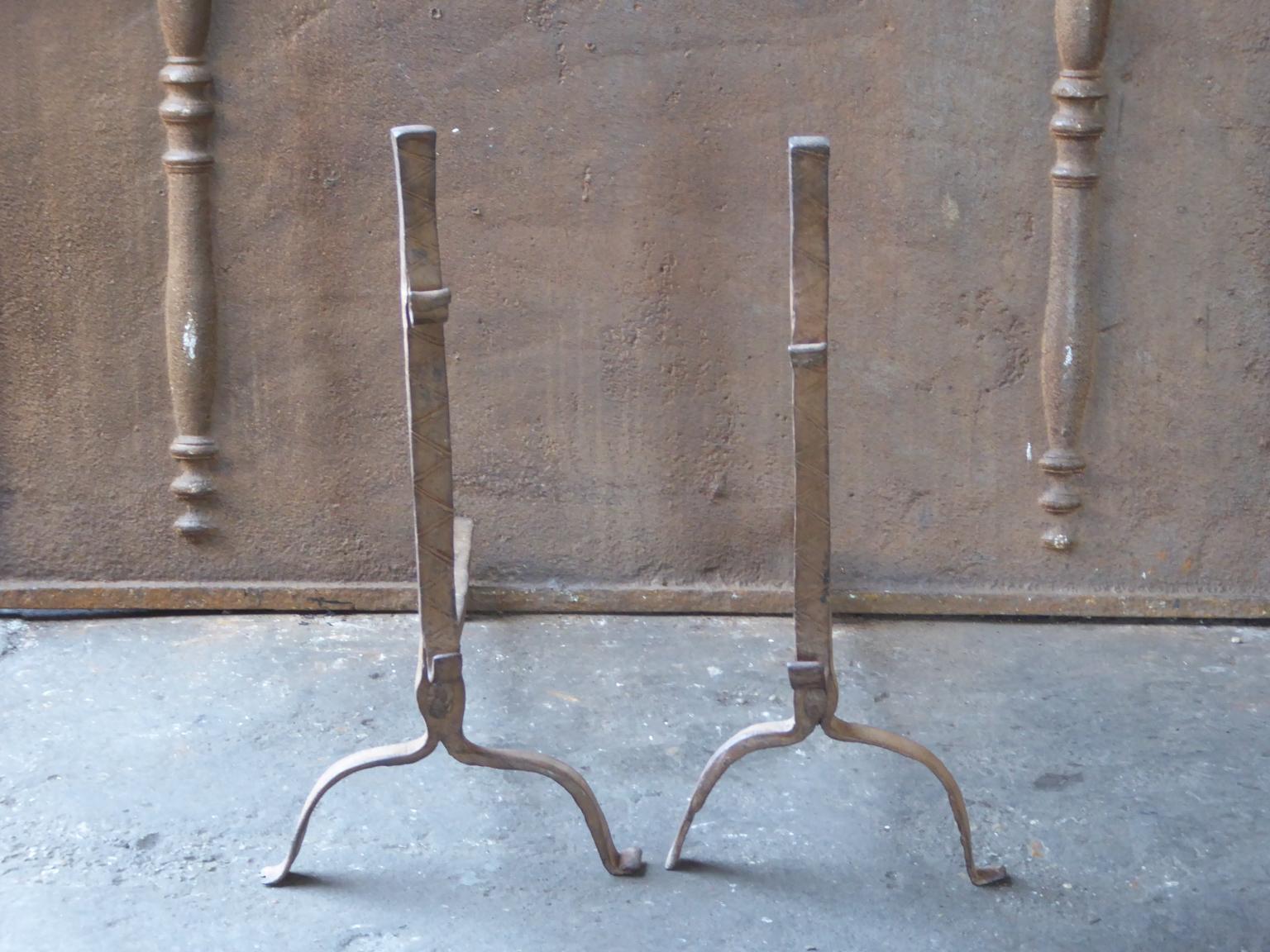 17th century French andirons made of wrought iron. The style of the andirons is Gothic. The andirons have spit hooks to grill food. They are in a good condition.