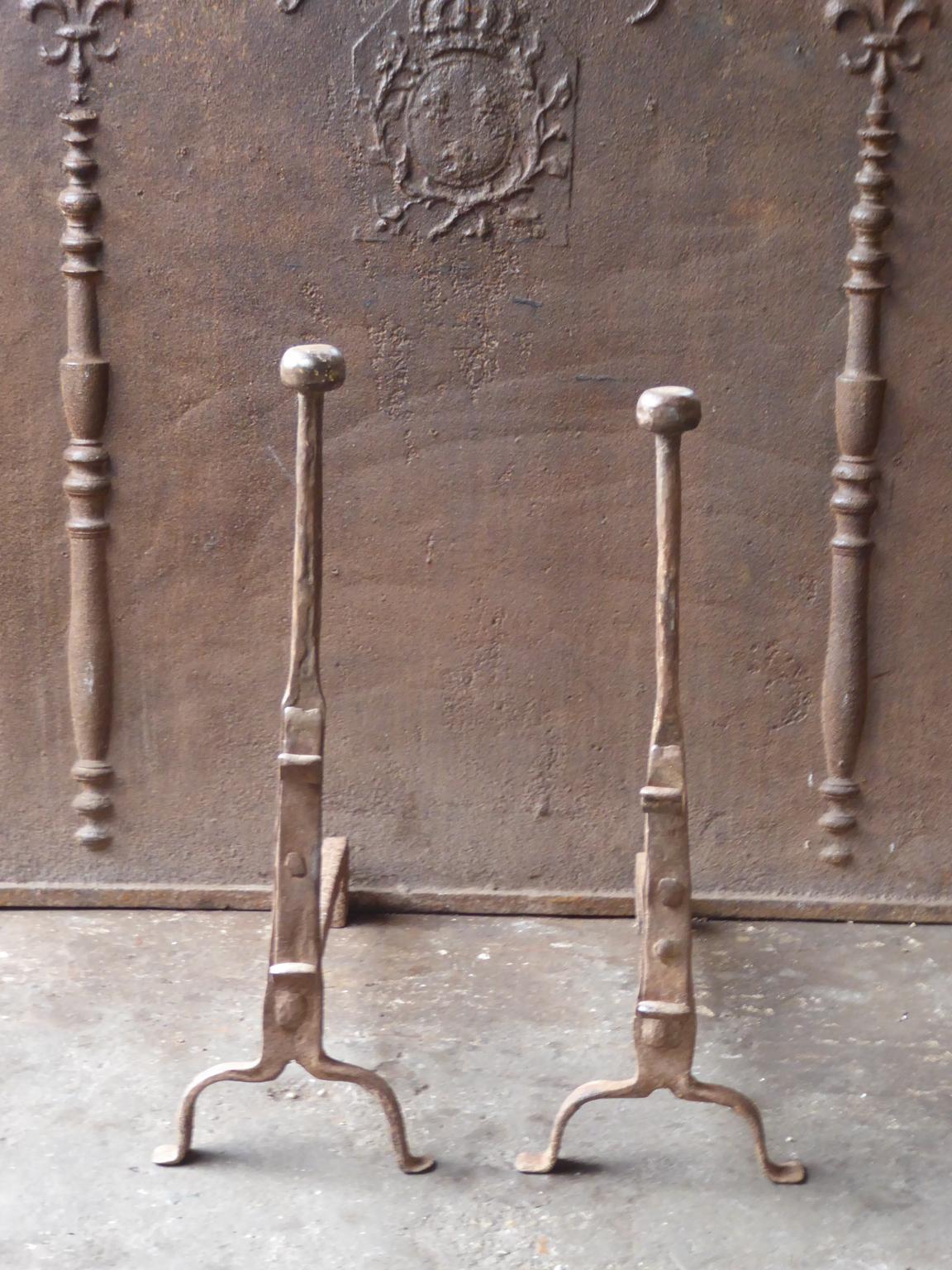 17th century French andirons made of wrought iron. The style of the andirons is gothic. The andirons have spit hooks to grill food. They are in a good condition.