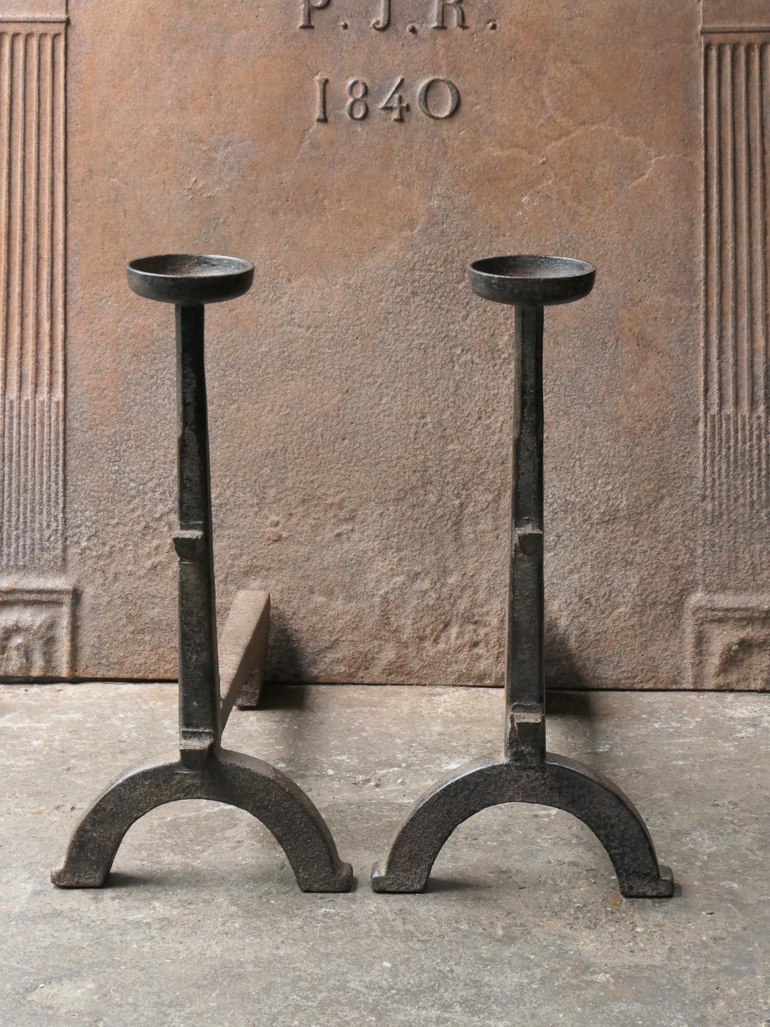French Gothic style fire dogs made of cast iron. With spit hooks to grill food and a cup to keep drinks or soup warm. This type of andirons are also called cupdogs.

We have a unique and specialized collection of antique and used fireplace