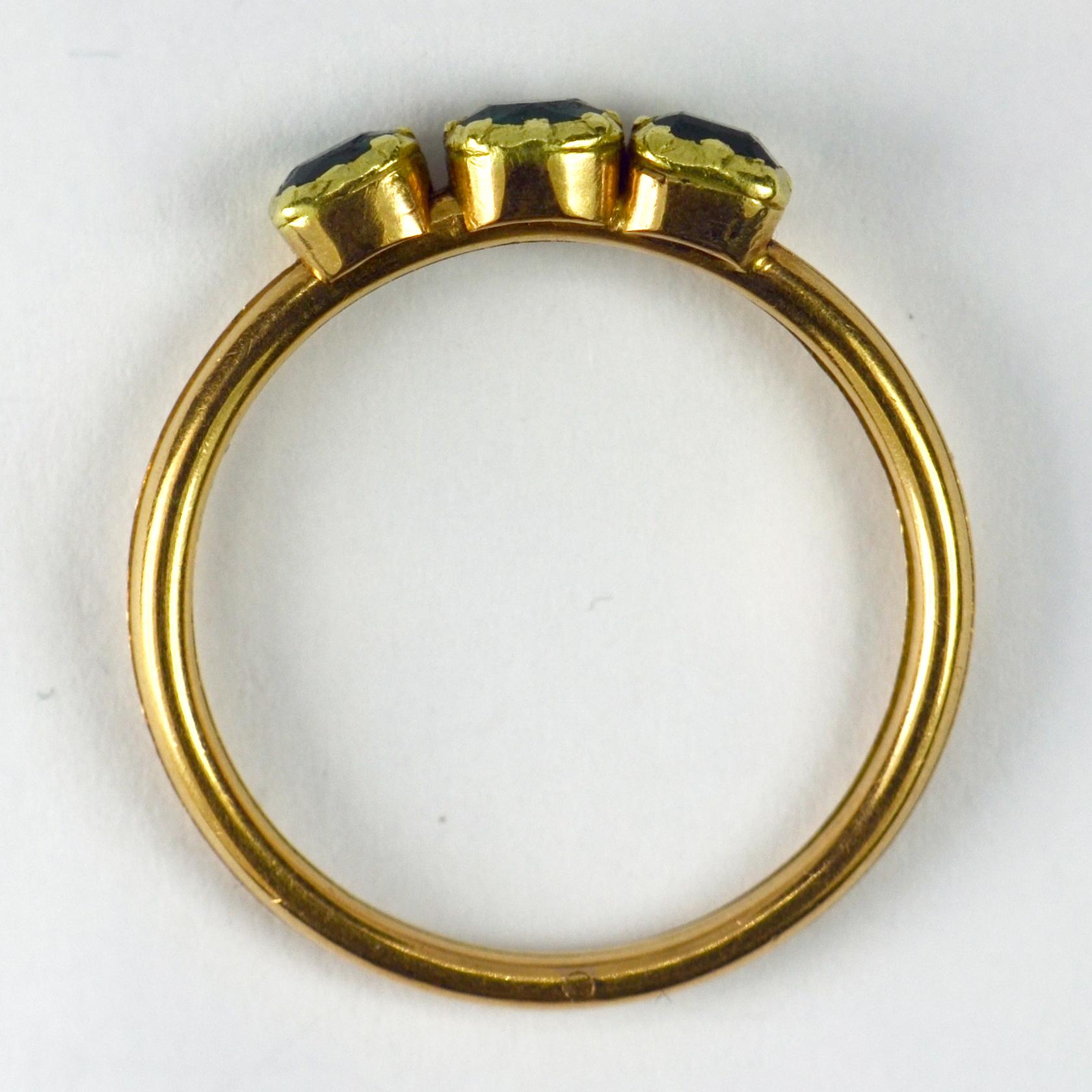 A French 18 karat (18K) yellow gold gimmel or fede ring with three hinged parts, each set with a collet set step cut green emerald. The three emeralds come together to form a trinity set when the ring is closed. Stamped with the eagles mark for 18