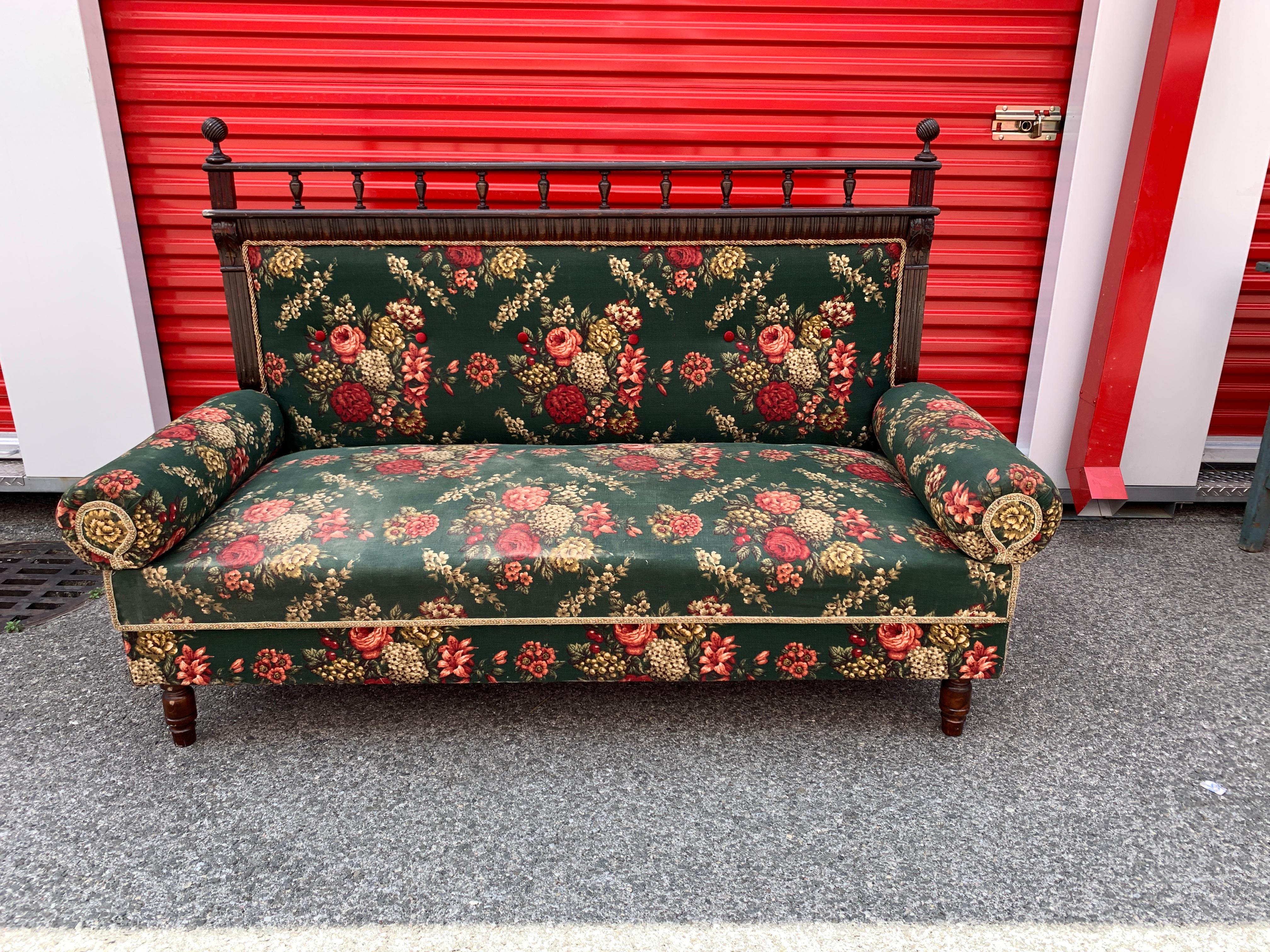 This antique French floral settee upholstered with a deep rich green fabric embellished with beautiful red and coral flowers brings a true sense of historic beauty. 

Arms and backing are both removable which makes storing and rearranging