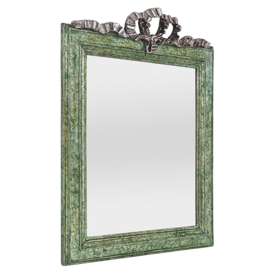 Antique French green colors mirror with a “marbled” patina effect, embellished with a small silvered pediment representing a stylized Louis XVI-style bow. Antique frame with a green patina and leaf gilding created by Atelier RTCD Paris. Frame width: