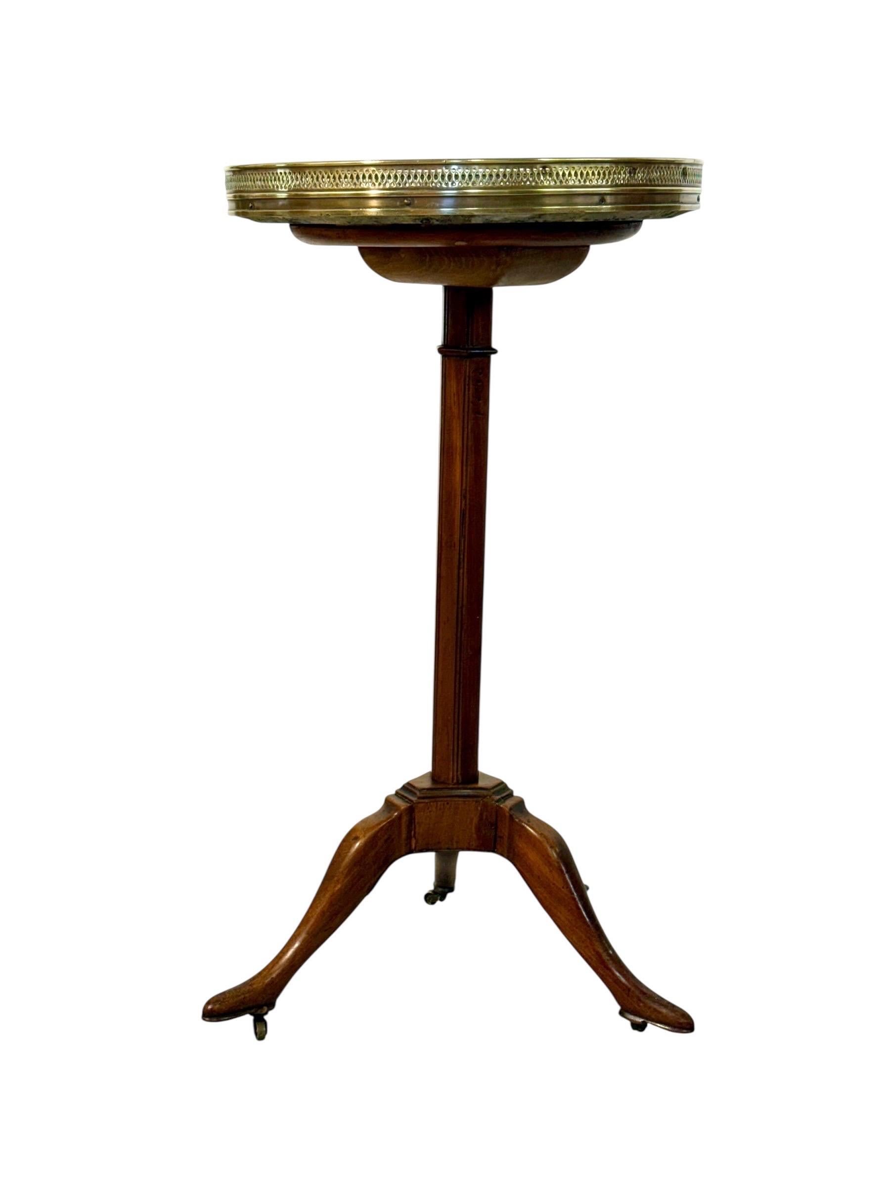 This elegant French guéridon table from the 19th century is a refined example of neoclassical taste, blending functionality with decorative artistry. The circular top is inset with a striking black and white marble surface, richly veined and full of