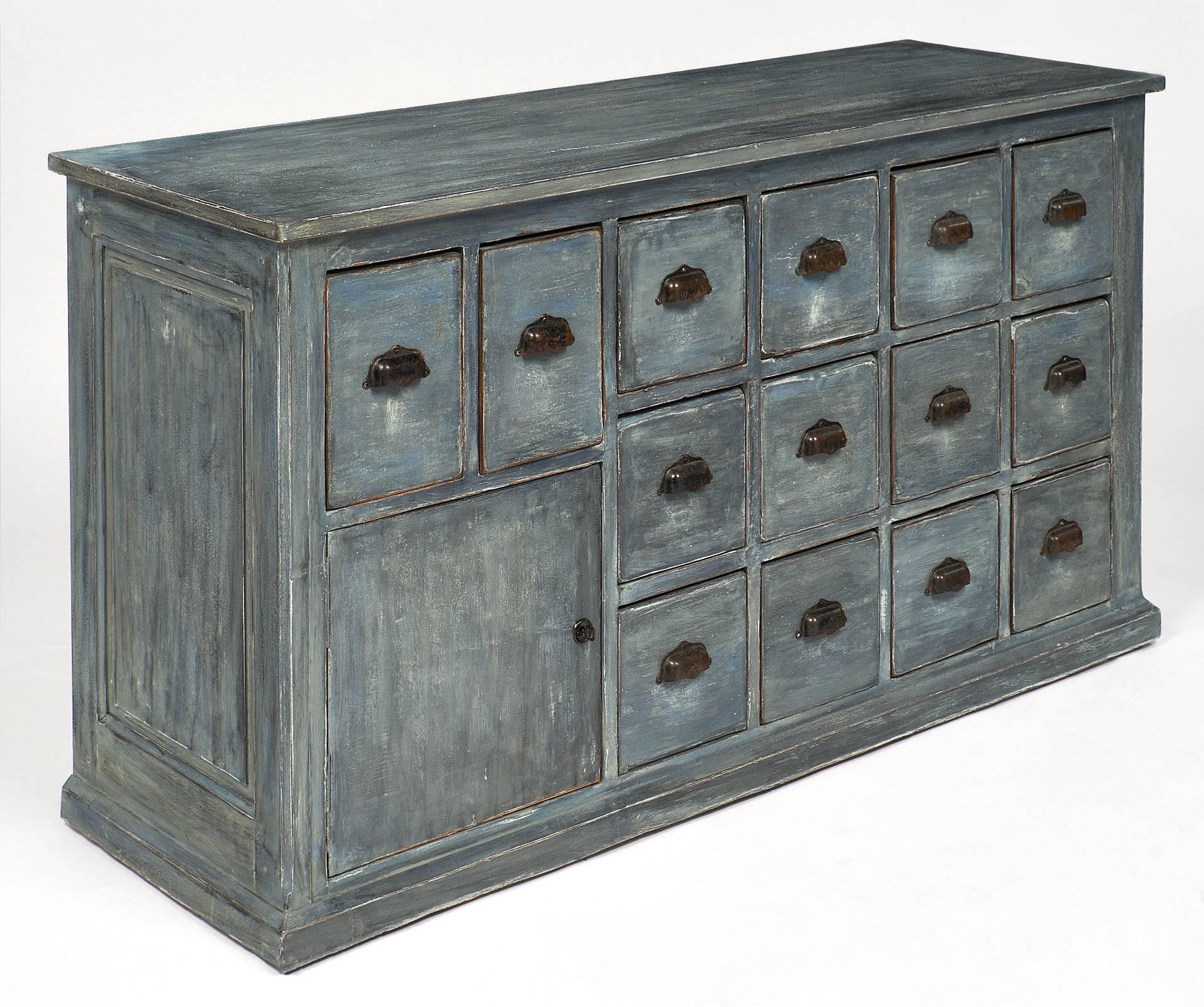 Painted French antique haberdashery cabinet of solid fir construction. This handsome industrial style piece features 14 drawers and a door, original handles and a patinated blue milk paint finish.