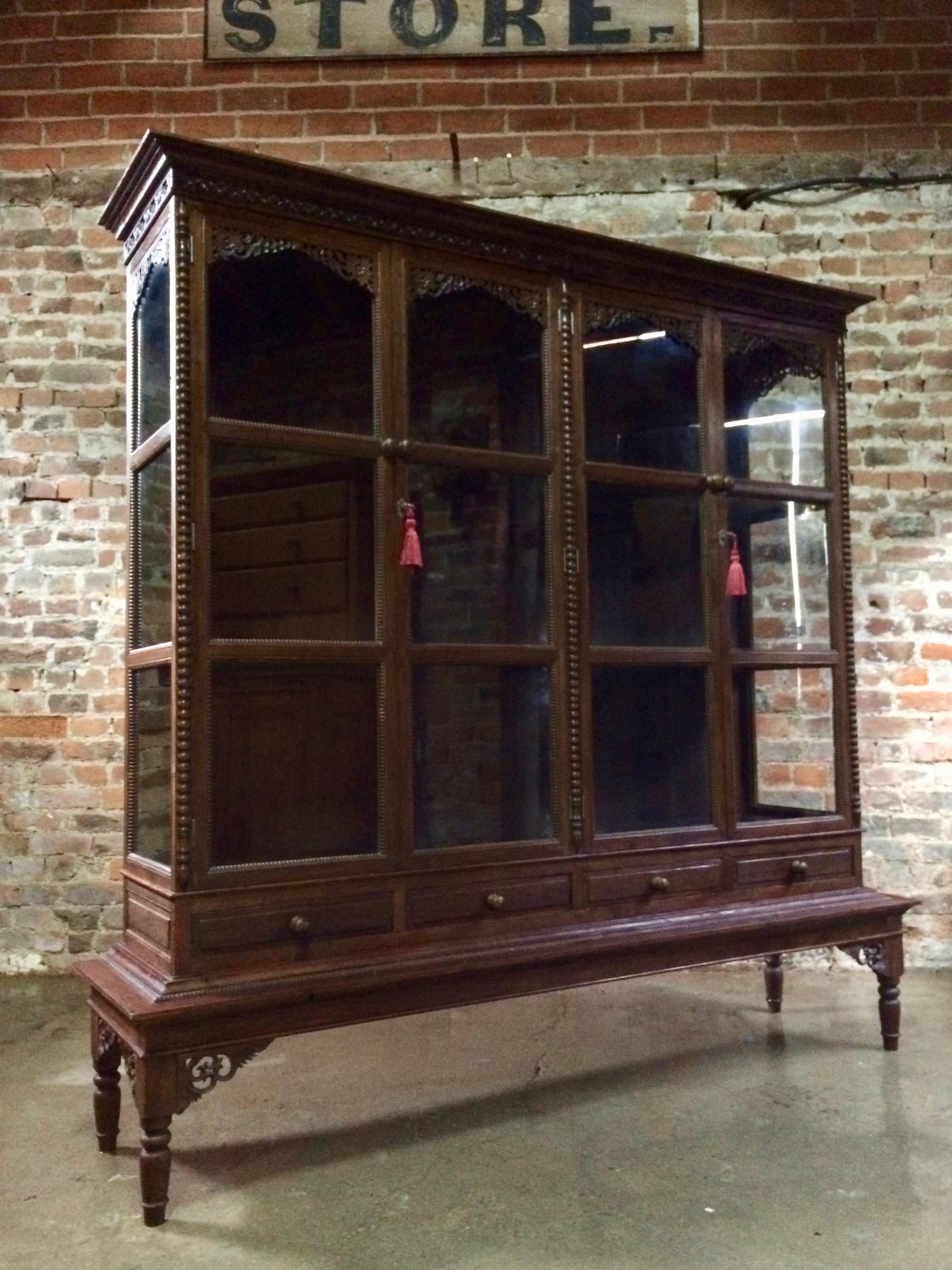 A fabulously large and imposing early 20th century French Haberdashery oak shop vitrine display cabinet circa 1920s, the ornate overhanging moulded carved cornice above four panelled glazed doors with floral fretwork to corners enclosing shelves