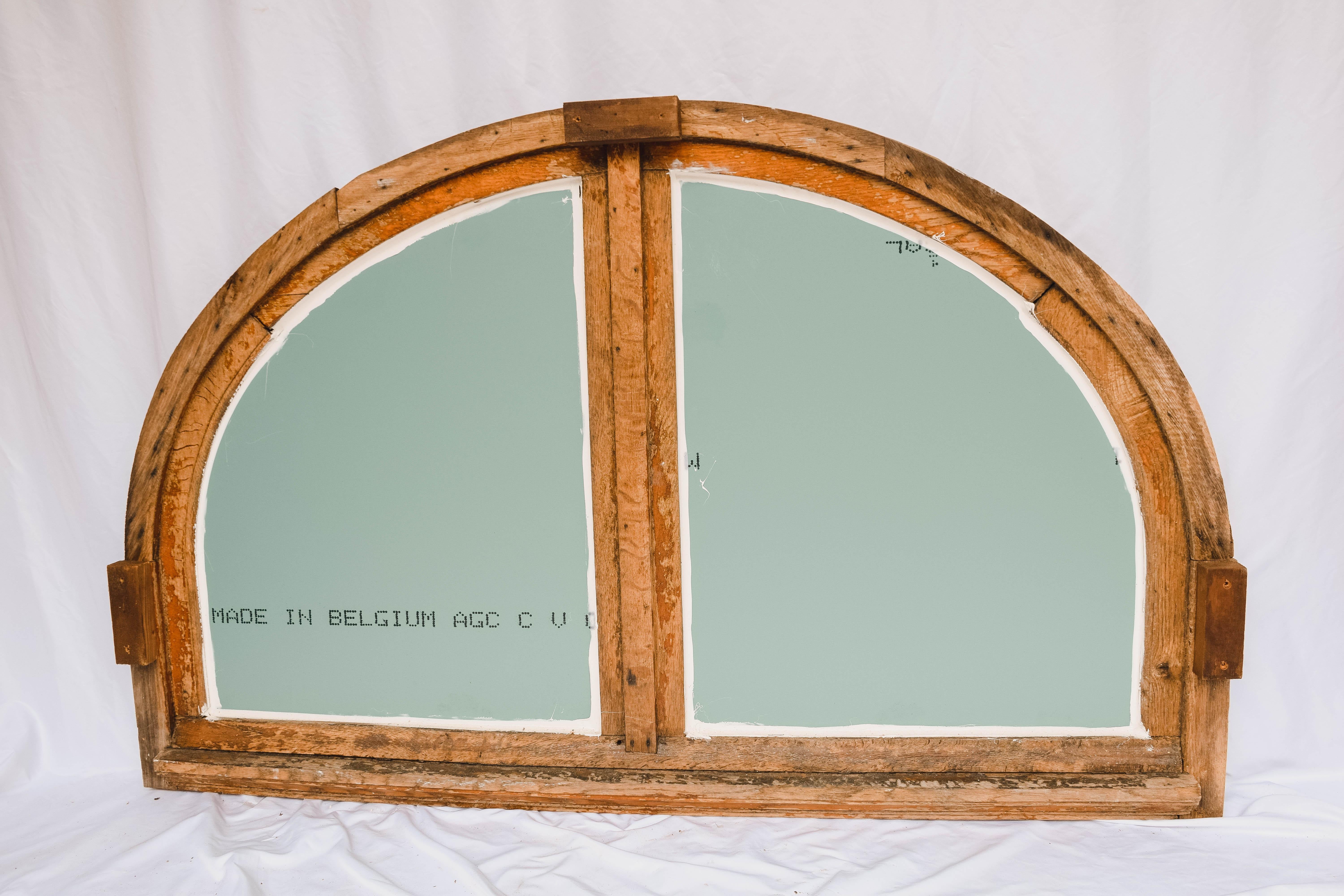 Found in France, this large antique French painted wood half round window casement has been repurposed as a mirror. This gorgeous antique French half-moon window/mirror features a painted wood casement divided into two halves. This piece retains