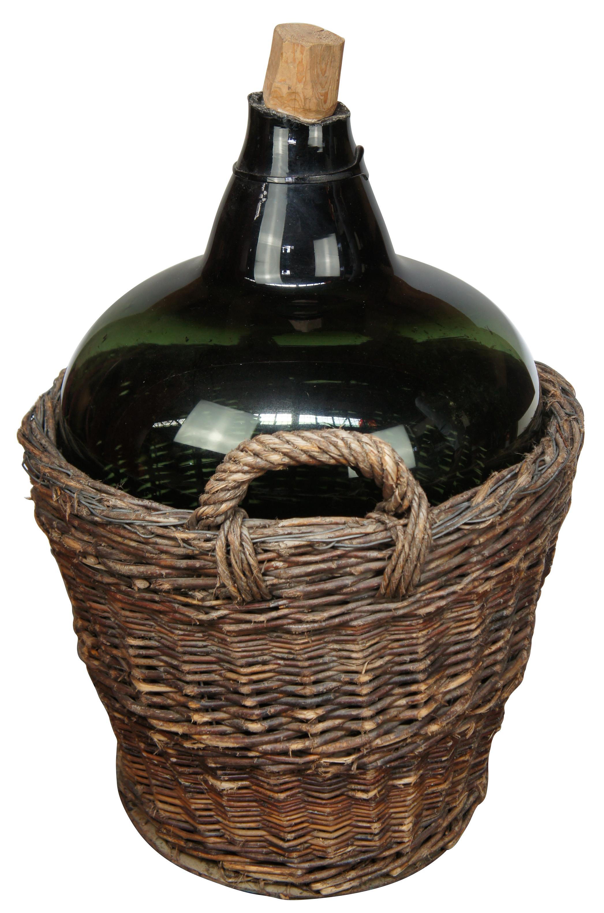 Antique hand blown green glass demijohn / bonbonne wine bottle in a woven wicker basket with handles.

Measures: 21.5