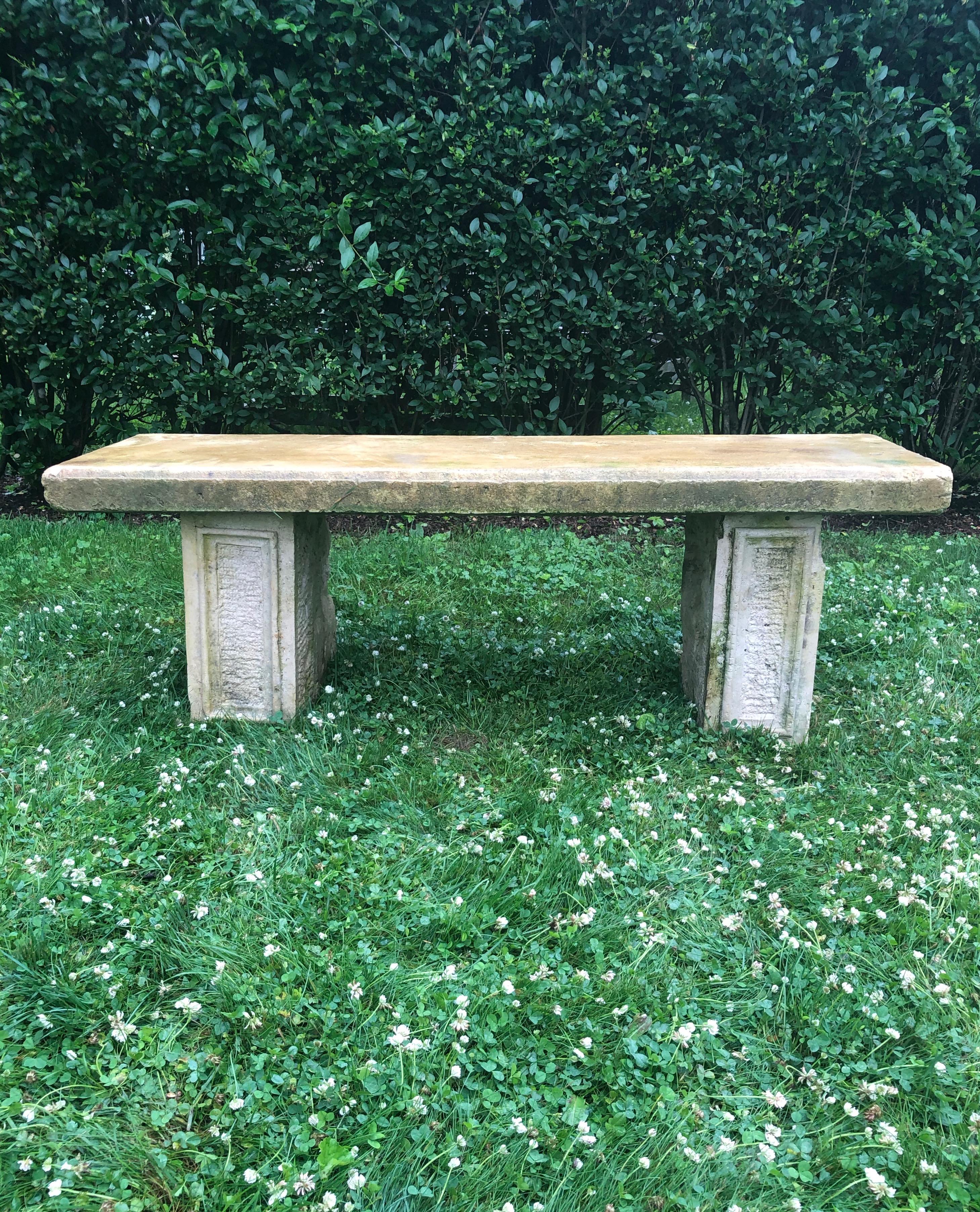 This lovely, simple bench is a marriage of a pair of hand-carved limestone supports from the mid-19th century and a carved limestone top from the 1930s. The top is slightly more yellow in color than the supports, especially in the rain, but we think