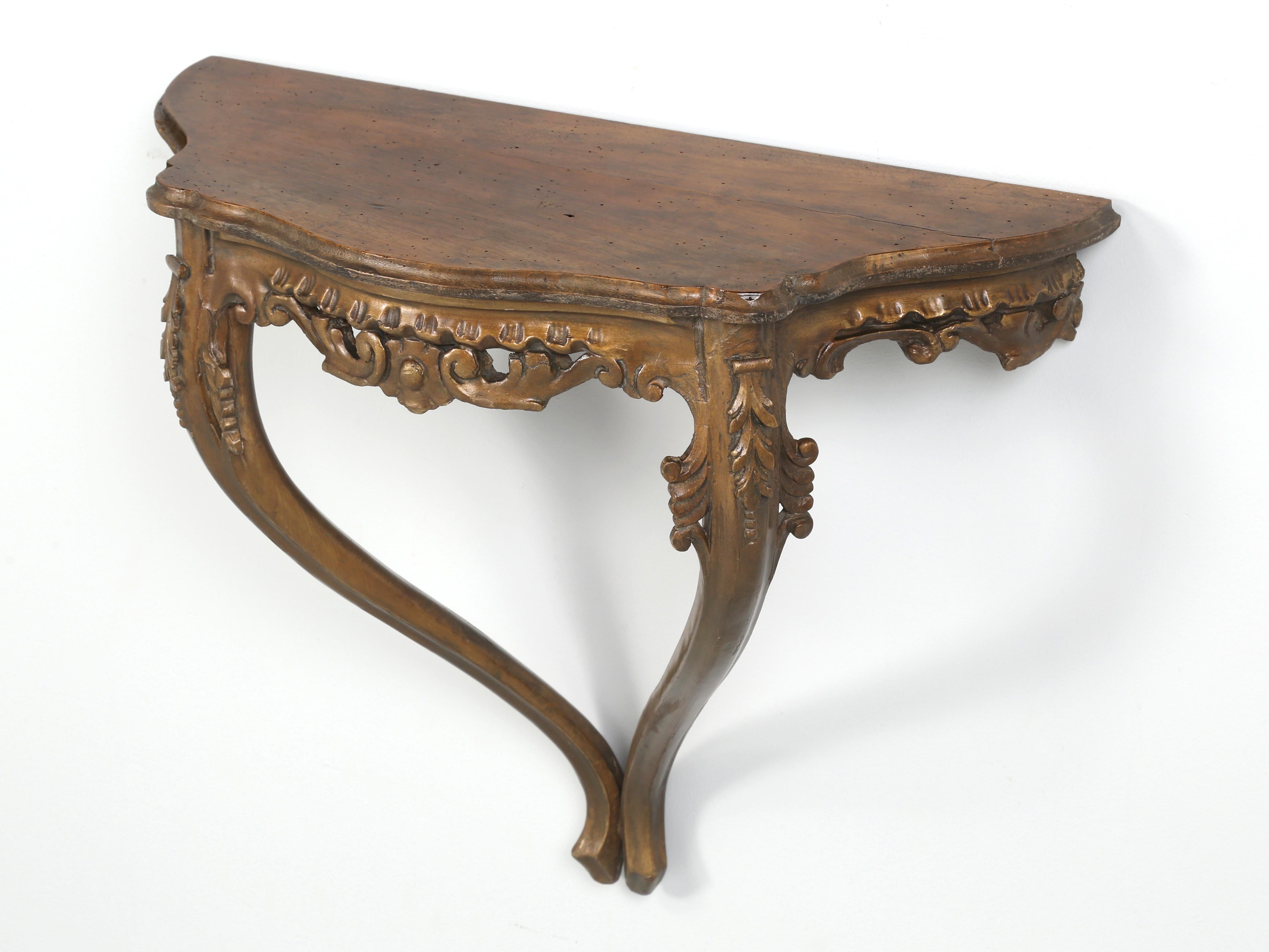 Antique French hand-carved wall-mounted console table probably made in the late 1800's or early 1900's. The finish appears to show some signs that it may have been originally gilded and over the last 100-years with each touch up, the gilding started