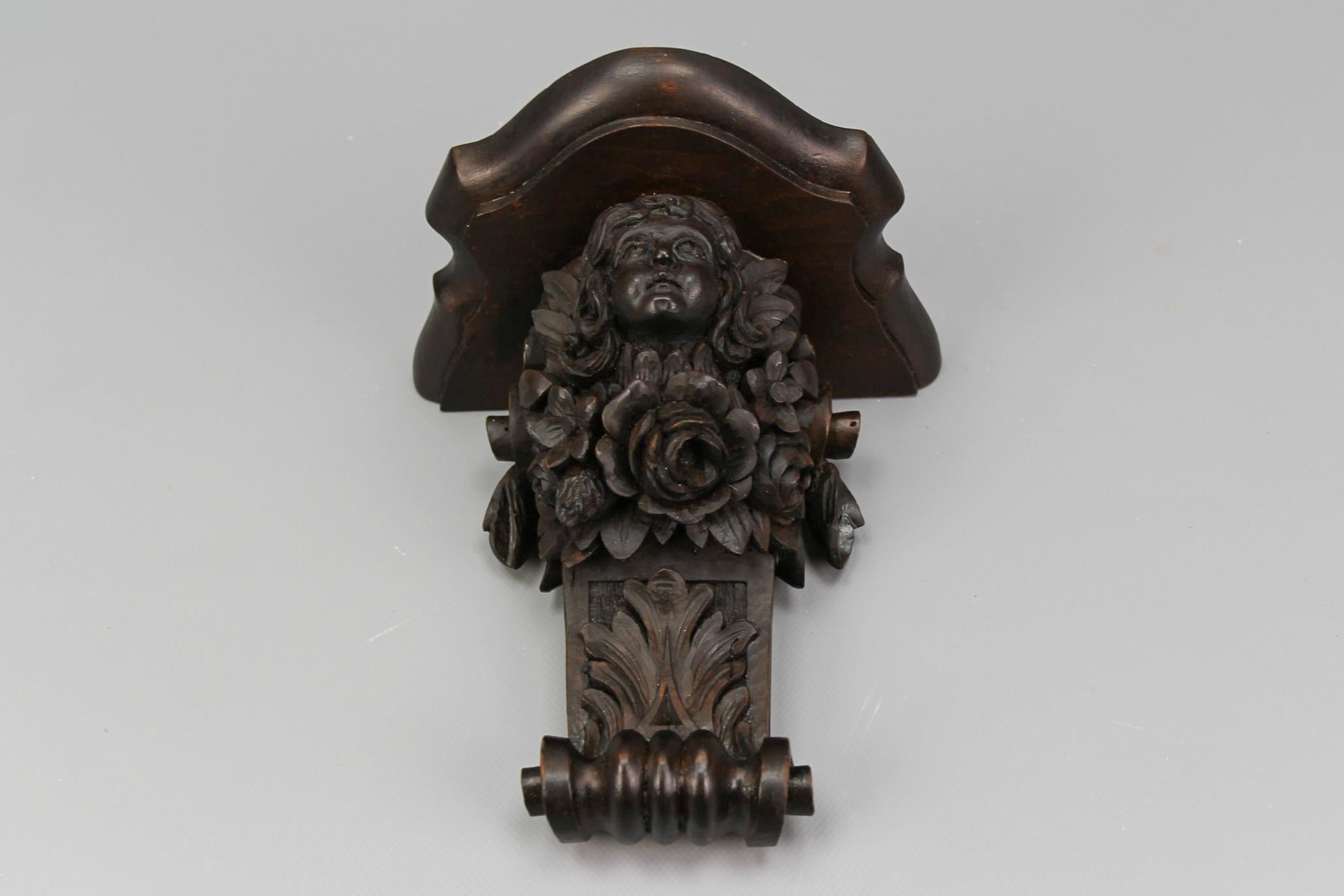 French Renaissance Revival hand-carved walnut wall bracket/shelf, from the early 20th century.
This beautiful and impressive antique wall console in dark brown features ornate flower and leaf carvings, centered with a carving of a face/head.
In good