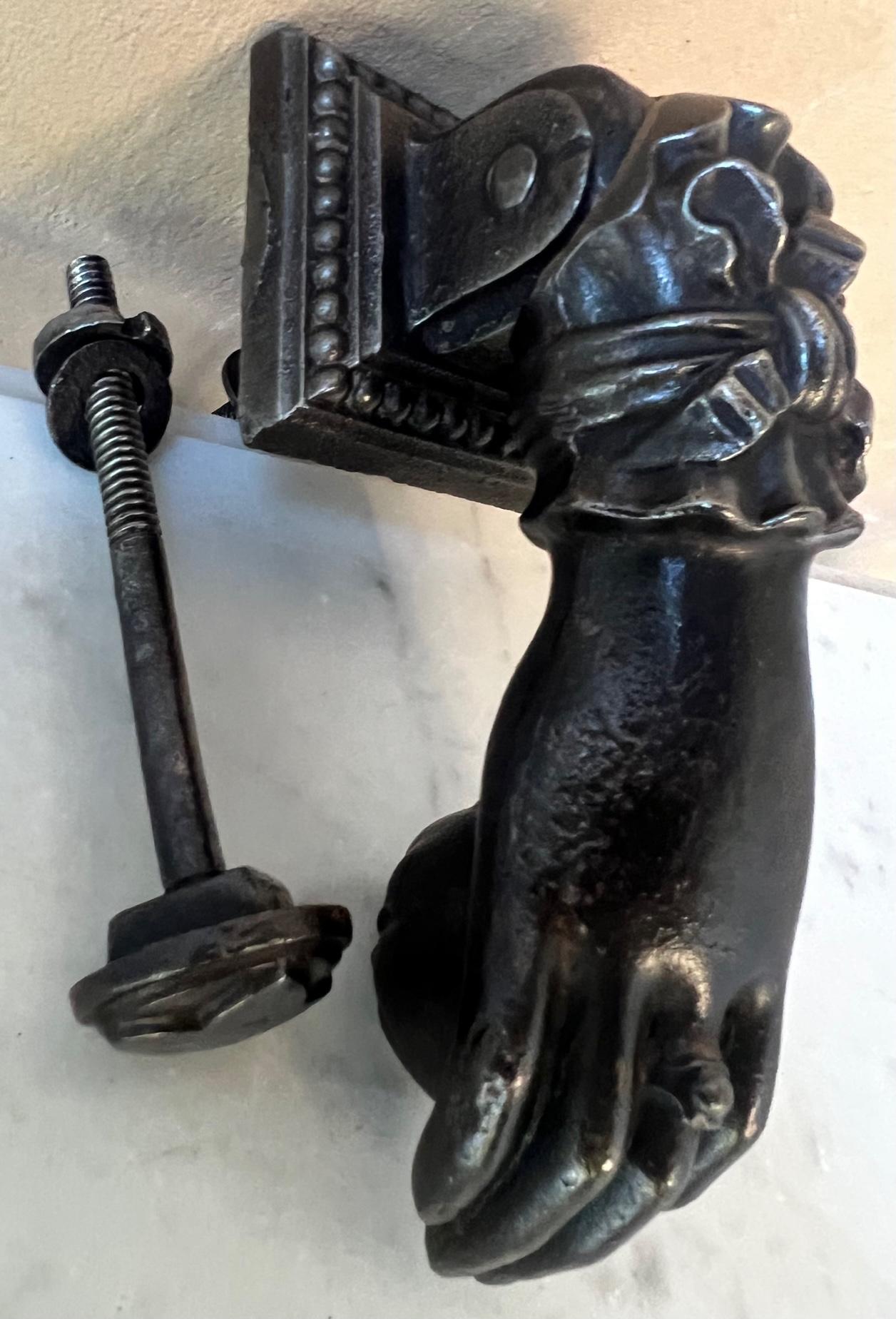 Classic French cast iron door knocker, in the shape of a ladies hand wearing a ring and a beautiful cuff, holding a ball. The set includes a round decorated back plate. Made in the mid to late 19th century.
Measurements taken when hand is hanging