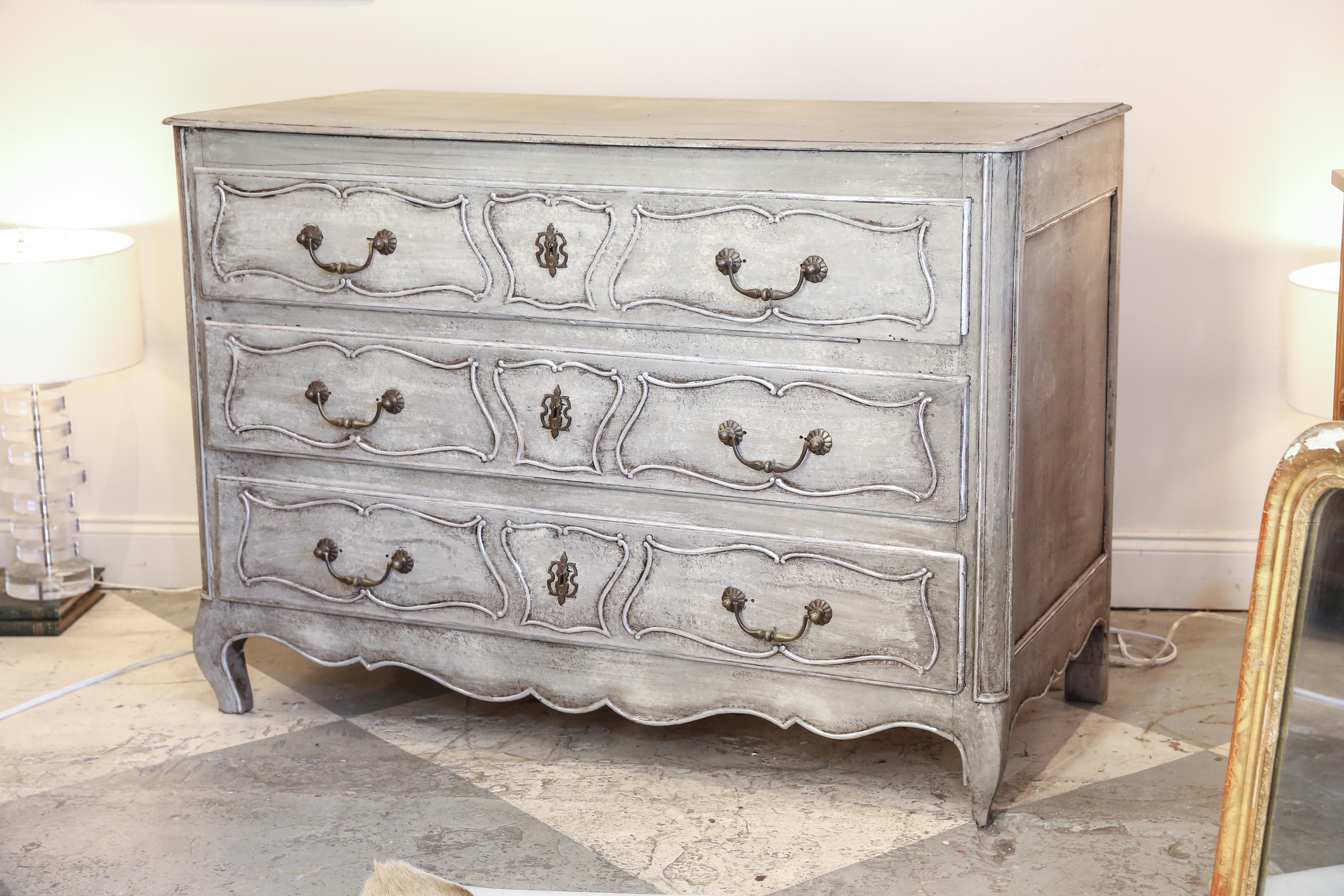 This is an antique Louis XVI style French commode that has been hand-painted in a divine greige with silver accents. The patinated brass hardware and ornate escutcheons complete this stunning chest of drawers. The interior of each drawer has also