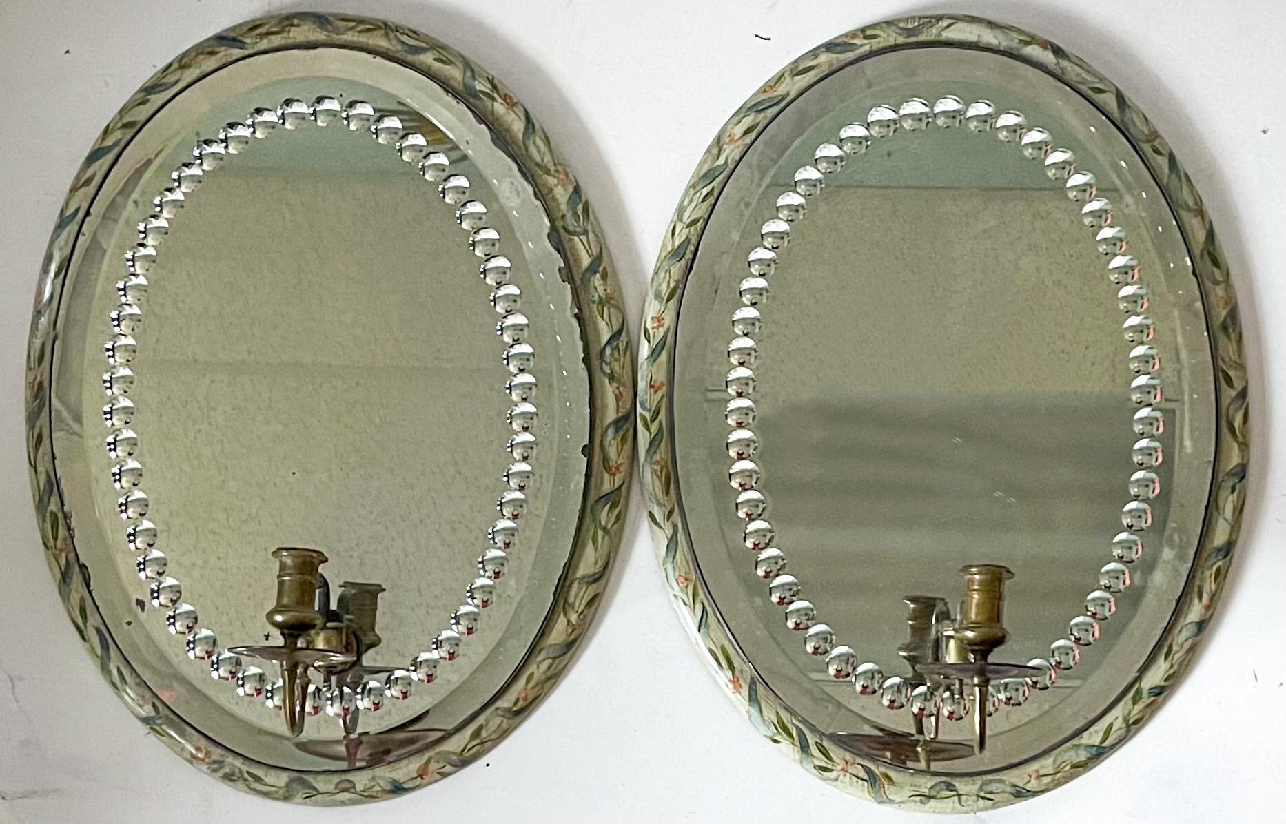 This isa pair of antique hand painted mirrored sconce with brass swing arm brass candle holder. The mirrored backs do show some age wear but no cracks. They are not electrified.