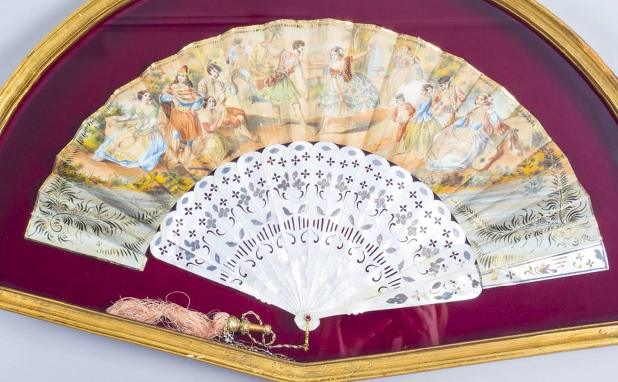 This is a beautiful decorative antique French mother-of-pearl fan set in a gilded frame dating from the late 19th century.

The fan is beautifully hand-painted with Romany ladies dancing and playing music, on richly gilt shaped and pierced