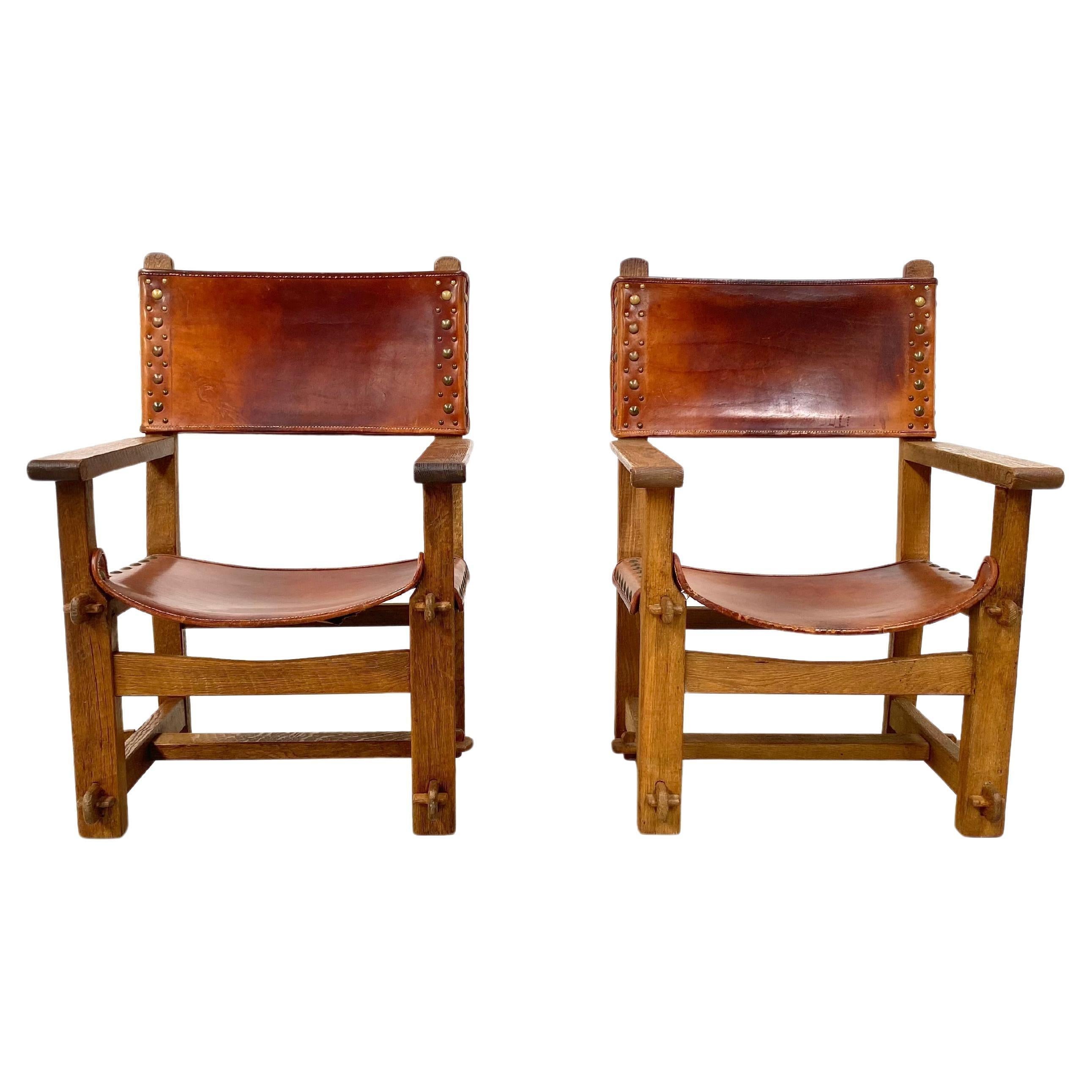 Set of 2 Antique Castle Chairs in thick Cognac leather and oak wood. It was handmade in France in the late twenties. Handmade only from wood and leather. The patinated solid oak frame is handcrafted and the connections are made with wooden bobbins