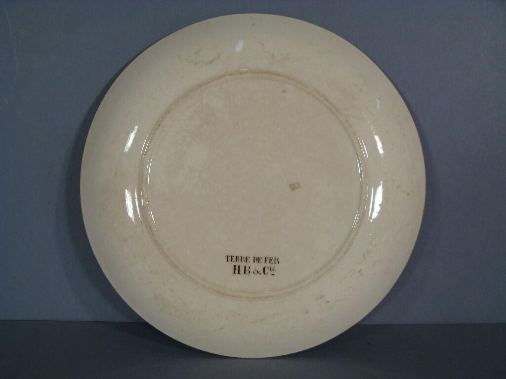 This exquisite antique French HB faience decorative plate commemorates the Madagascar Campaign of the early 20th century. Handcrafted from fine earthenware, the plate features a captivating design that showcases the rich history and culture of