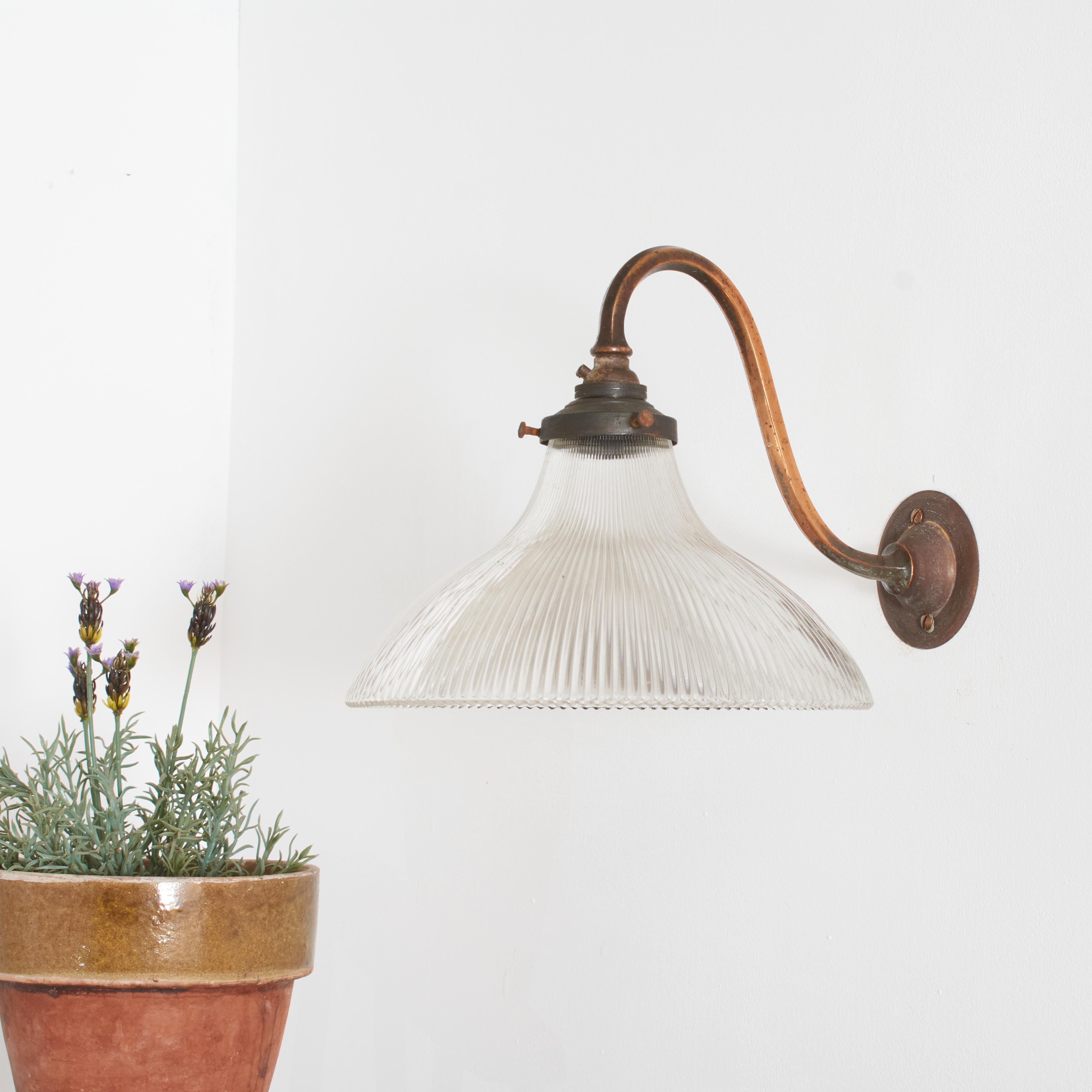 Antique Glass Holophane Wall Light – D

A vintage bell shaped glass prismatic light shade which looks great both lit and unlit. The light has retained its original brass gallery and wall bracket, which has some great age and painta. The glass shade