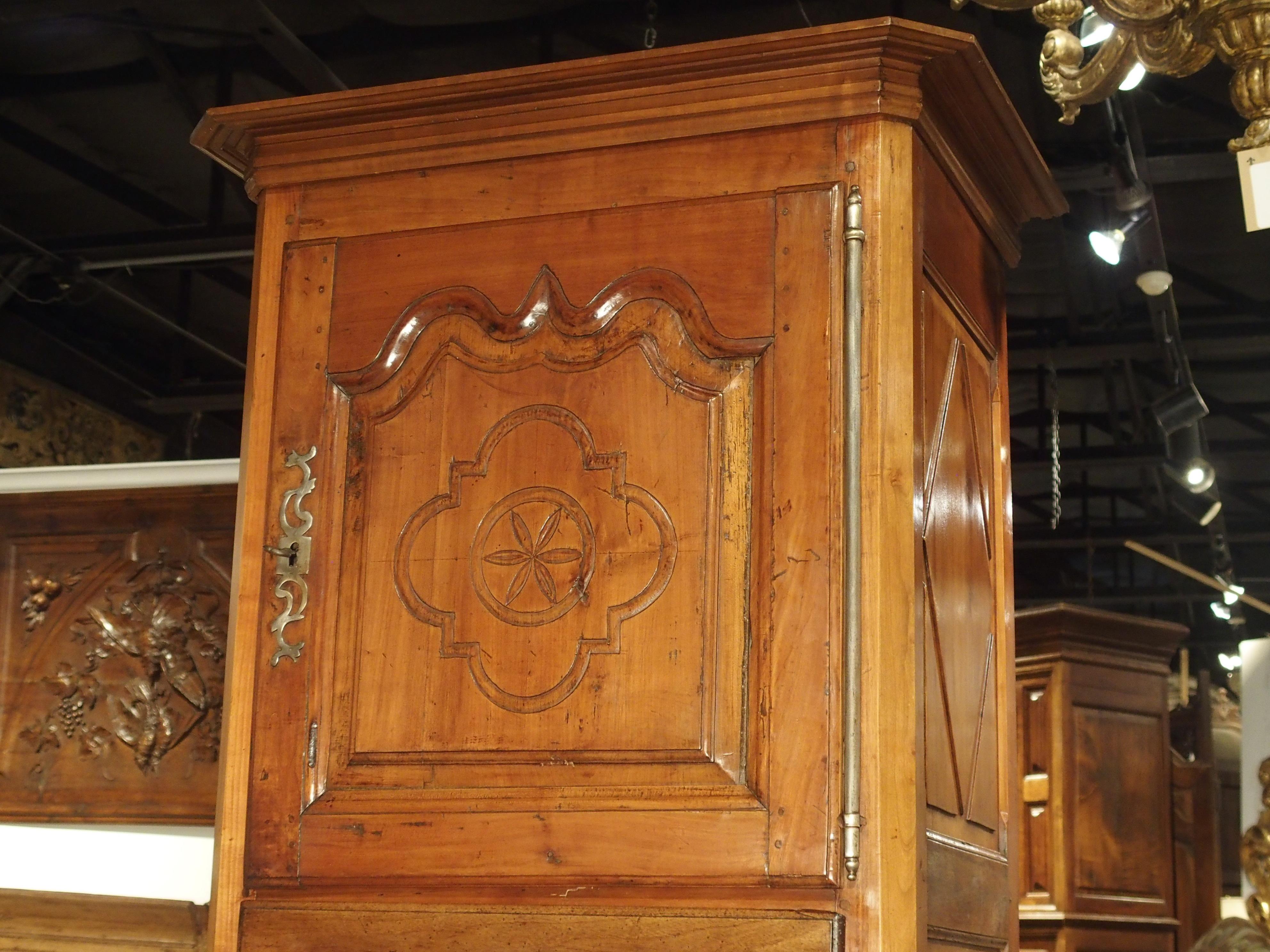 This elegant French cabinet has been carved out of cherrywood during the mid-1800s. It is characterized by having a much narrower body than a normal armoire, as well as having an upper and lower door, separated by a center drawer. Many of the oldest