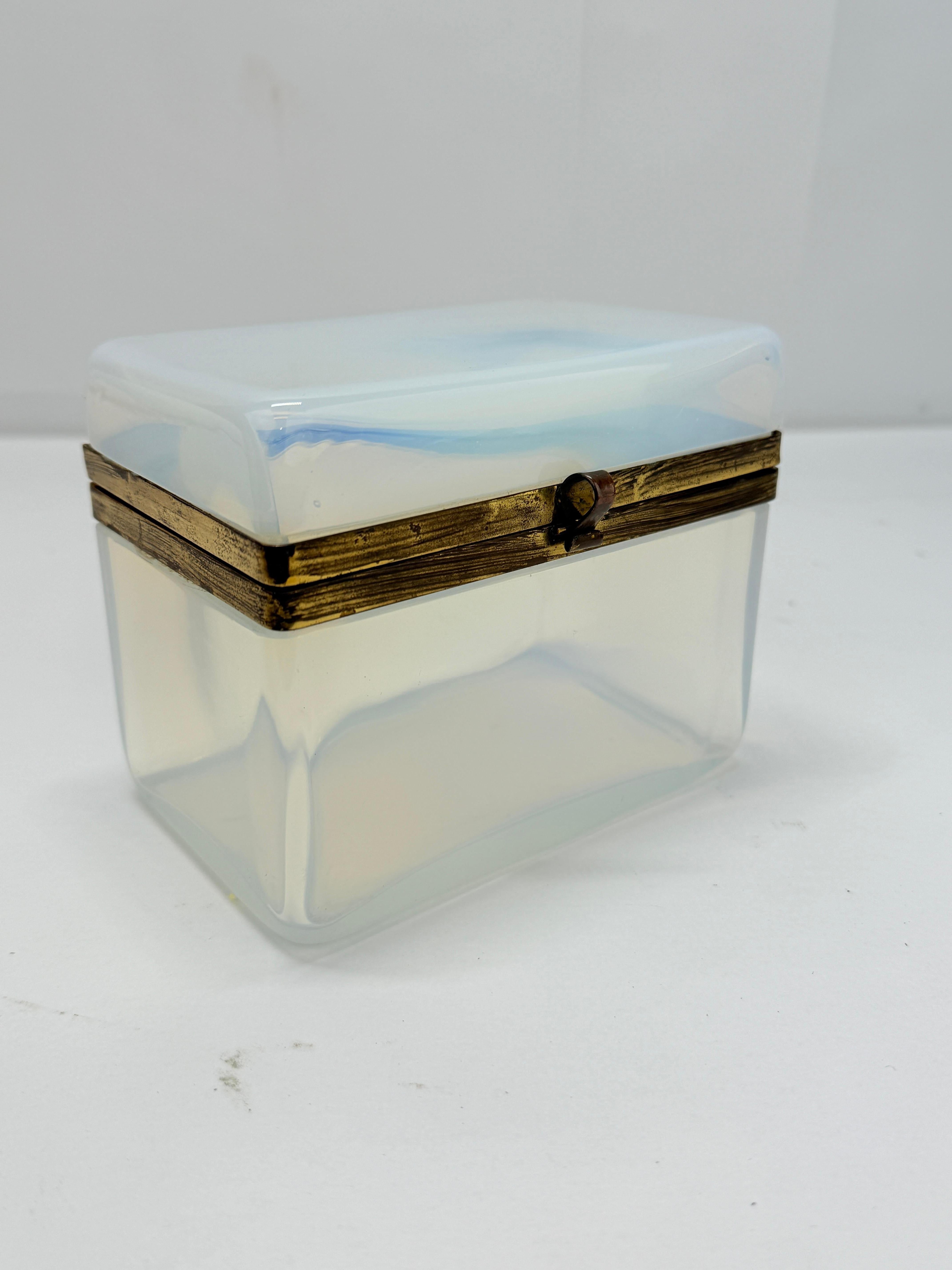 This stunning antique French box is crafted from icy blue opaline glass, a material prized for its luminous, semi-translucent quality and refined elegance. The smooth, polished surface radiates a cool, ethereal glow, characteristic of fine opaline