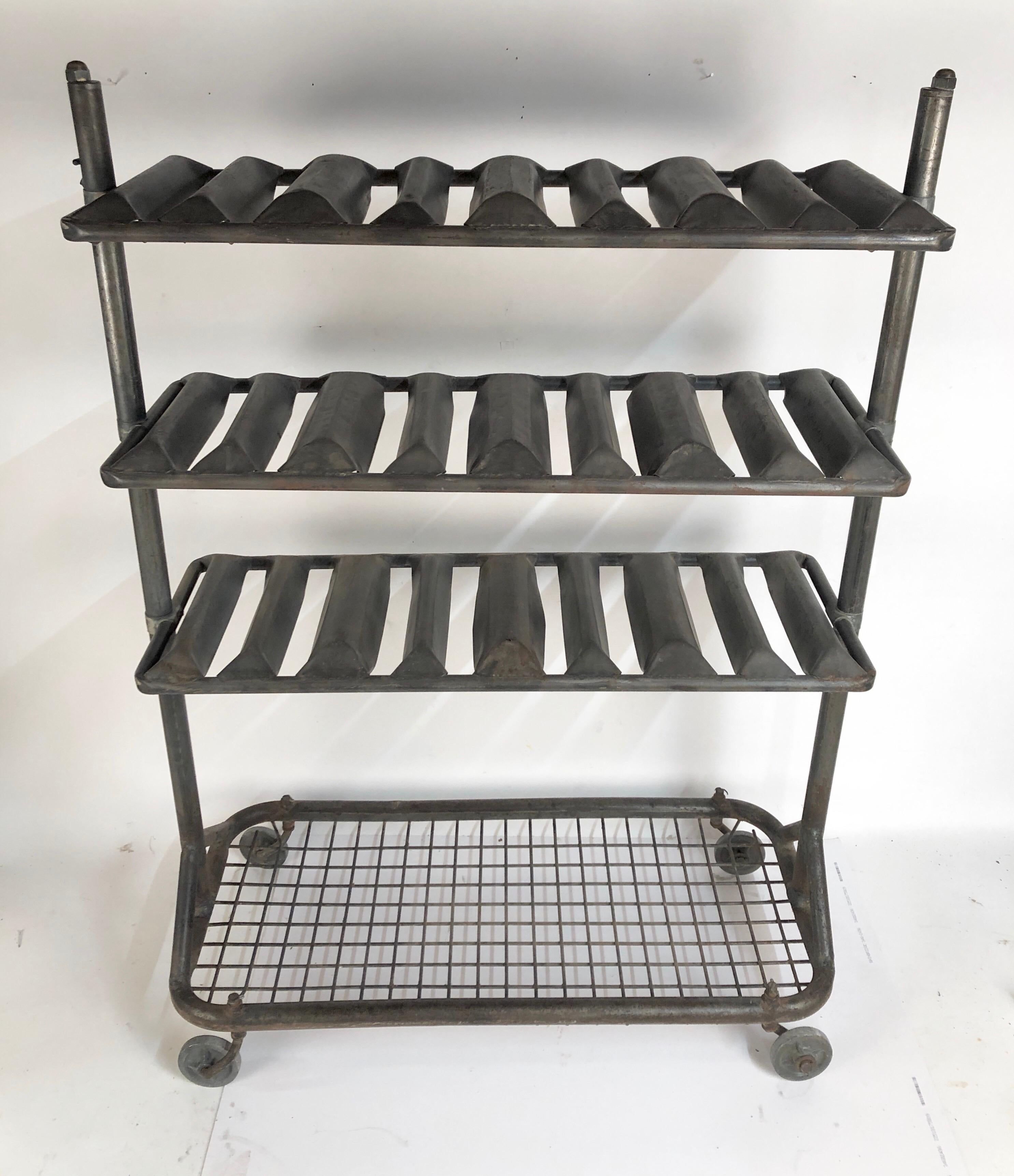 A circa 1930s French industrial steel drying rack that works perfectly for holding 24 bottles of your favorite wine. Also has a metal grid at the bottom for additional storage. Glass shelves can be added to use for other displays. Terrific wheels.