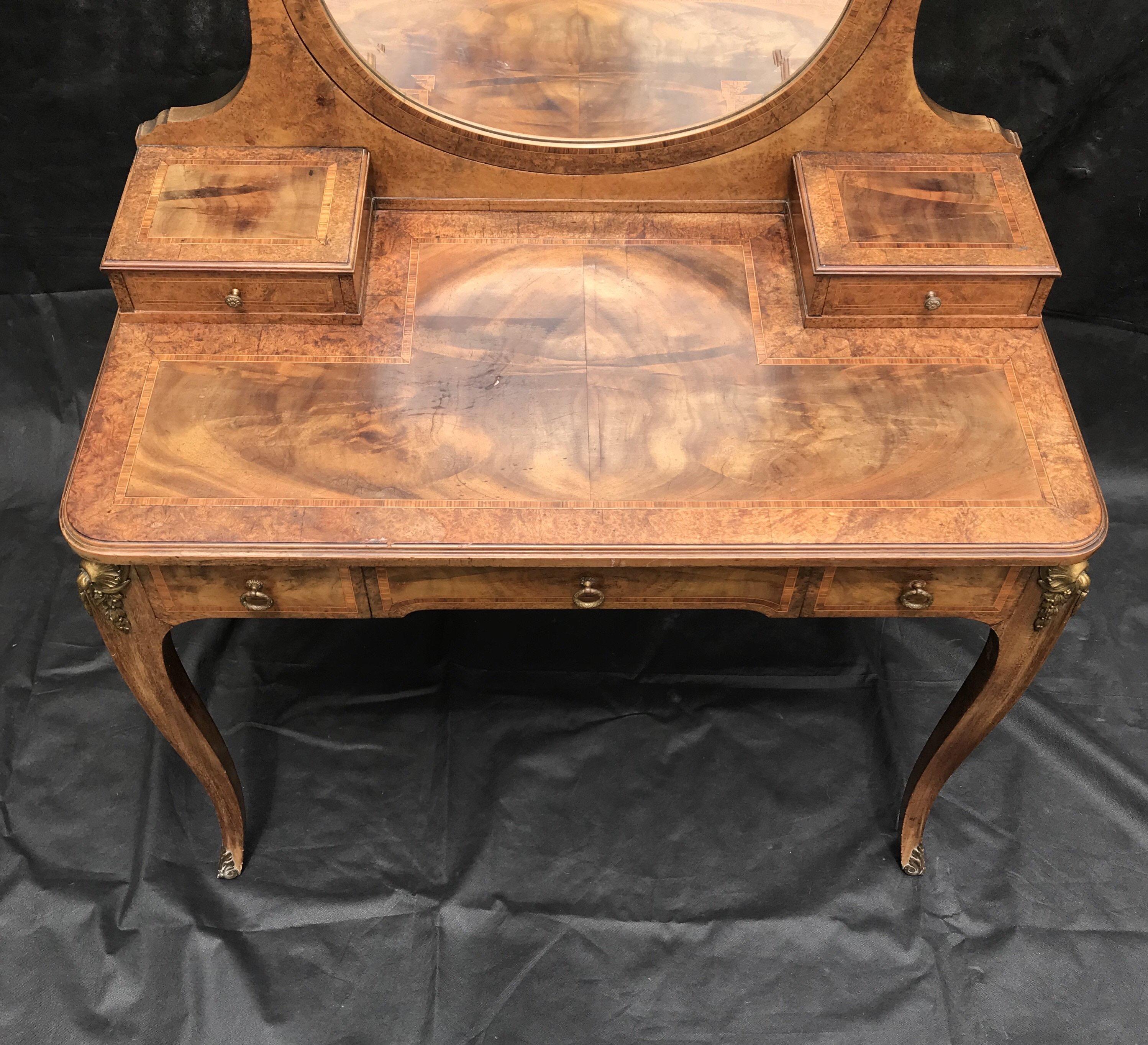 Bought outside Paris, a 19th century gorgeous antique inlaid walnut vanity having marquetry and faithful interpretation of the Louis XV style with three spacious drawers. A graceful oval shaped beveled vanity mirror tops this impeccable design,