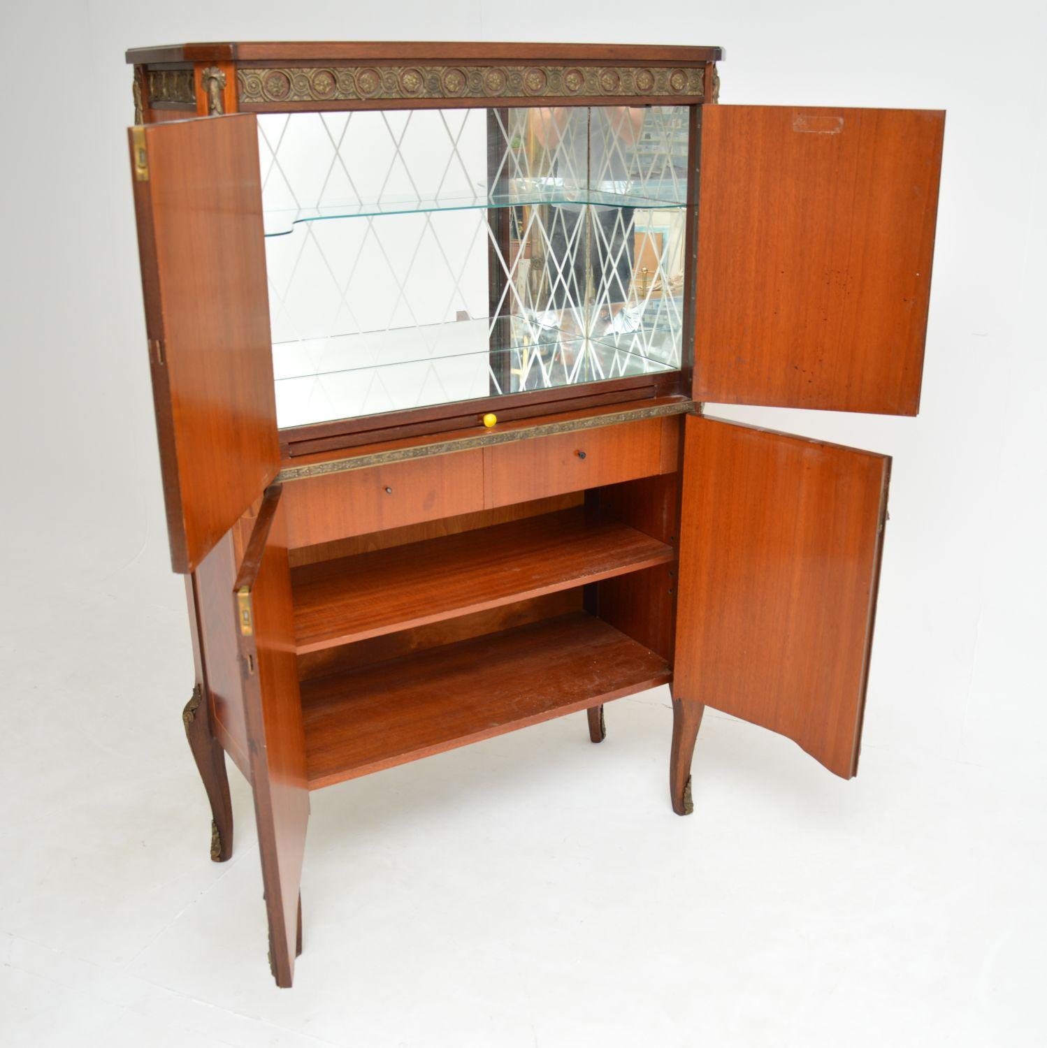 A stunning antique French cocktail drinks cabinet, inlaid with various woods with gilt bronze mounts, dating from around the 1930’s.

The quality is fantastic, this is extremely well made and exquisitely decorated. It is made from walnut and