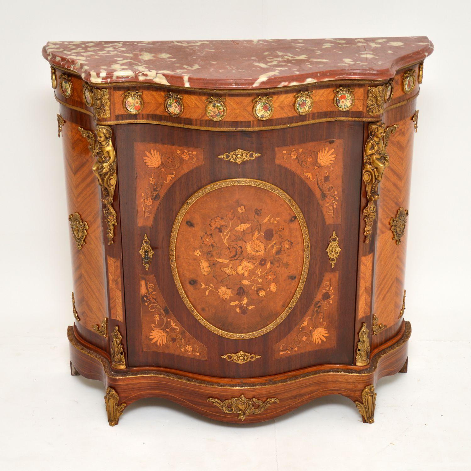 This antique French style marble top cabinet has lovely small proportions and is in very good condition, dating from circa 1930s period.

It has a serpentine shaped front and many colourful different woods, like Kingwood, satinwood, walnut,