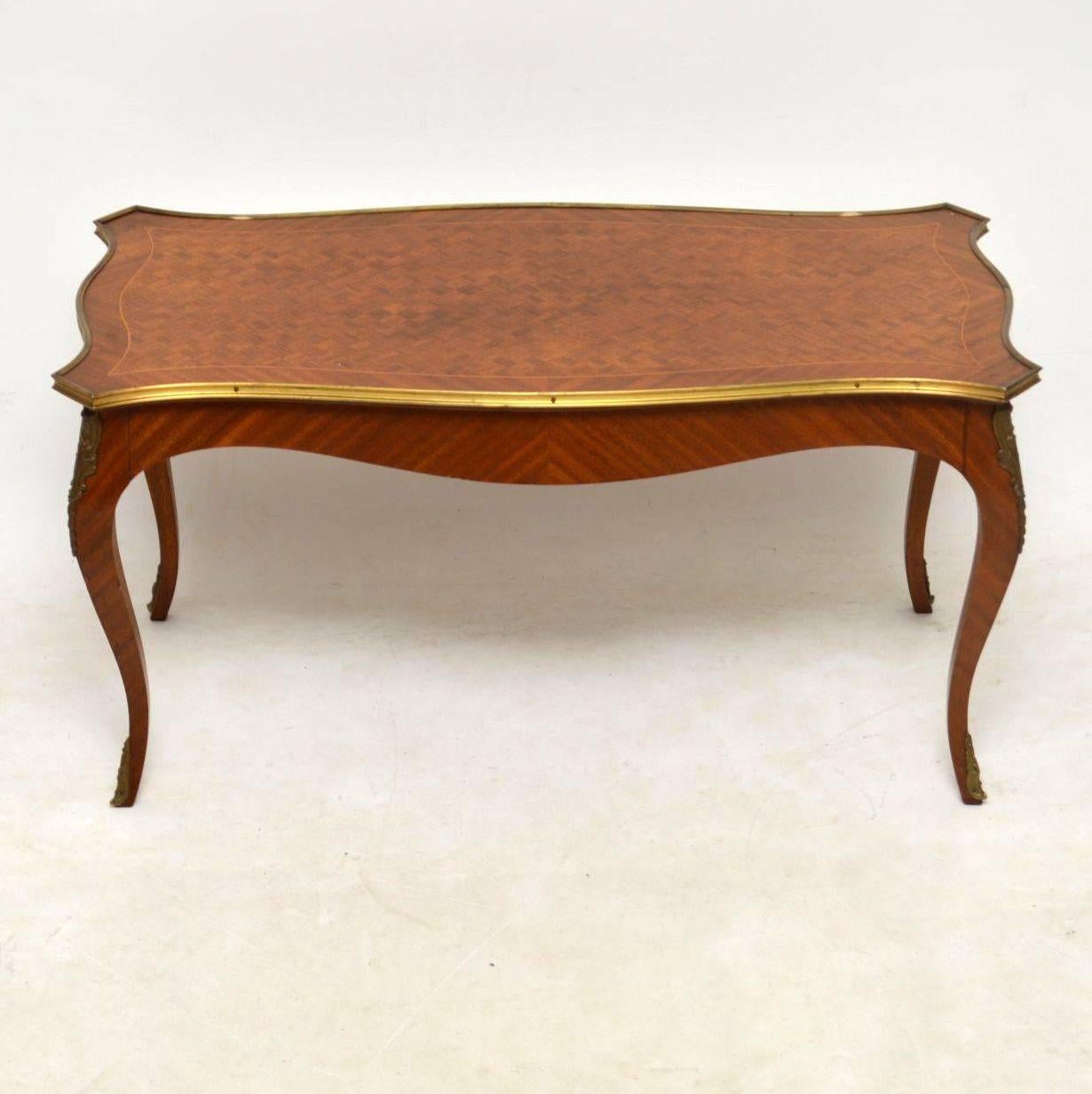 Antique French kingwood coffee table with a parquetry top, inlaid and cross banded around the edge. It has a gilt metal top edge and gilt mounts on the legs. This table dates from around the 1920s period and is in good original condition, with a few