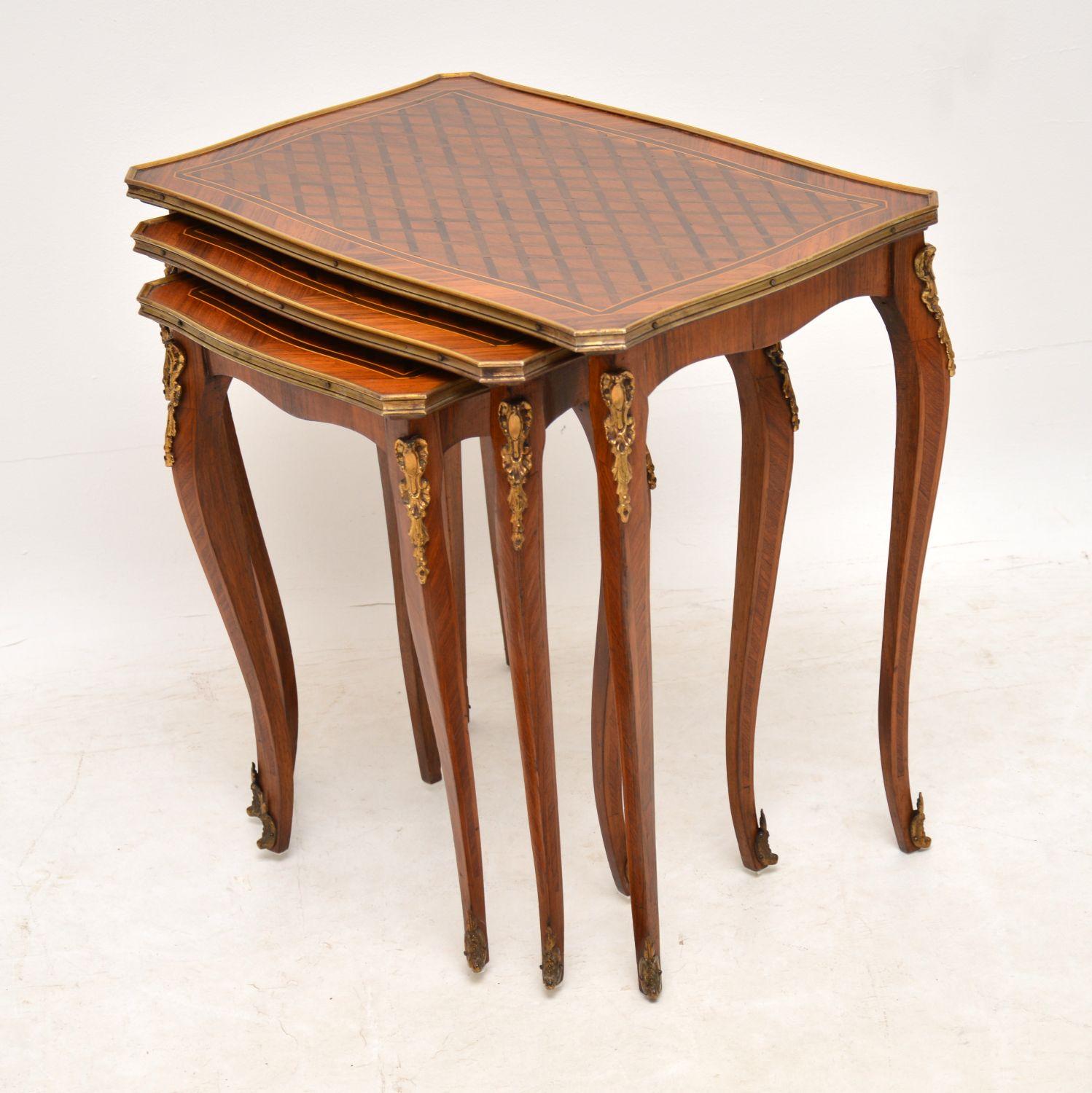 Antique French kingwood and rosewood nest of three tables with inlaid and parquetry tops of various exotic woods. The tops were well designed and date from circa 1920s-1930s period. They have a gilt bronze edges and finely detailed gilt mounts.