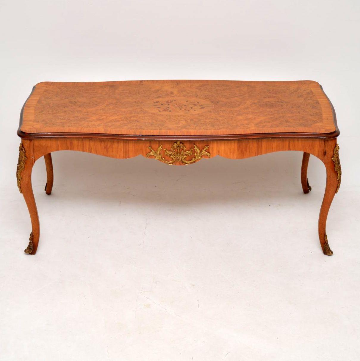 This antique French walnut coffee table has some beautiful burr walnut veneers on the top, plus a floral marquetry design inset into a central oval panel. The top is also cross banded with figured walnut and has other inlaid features. This table has